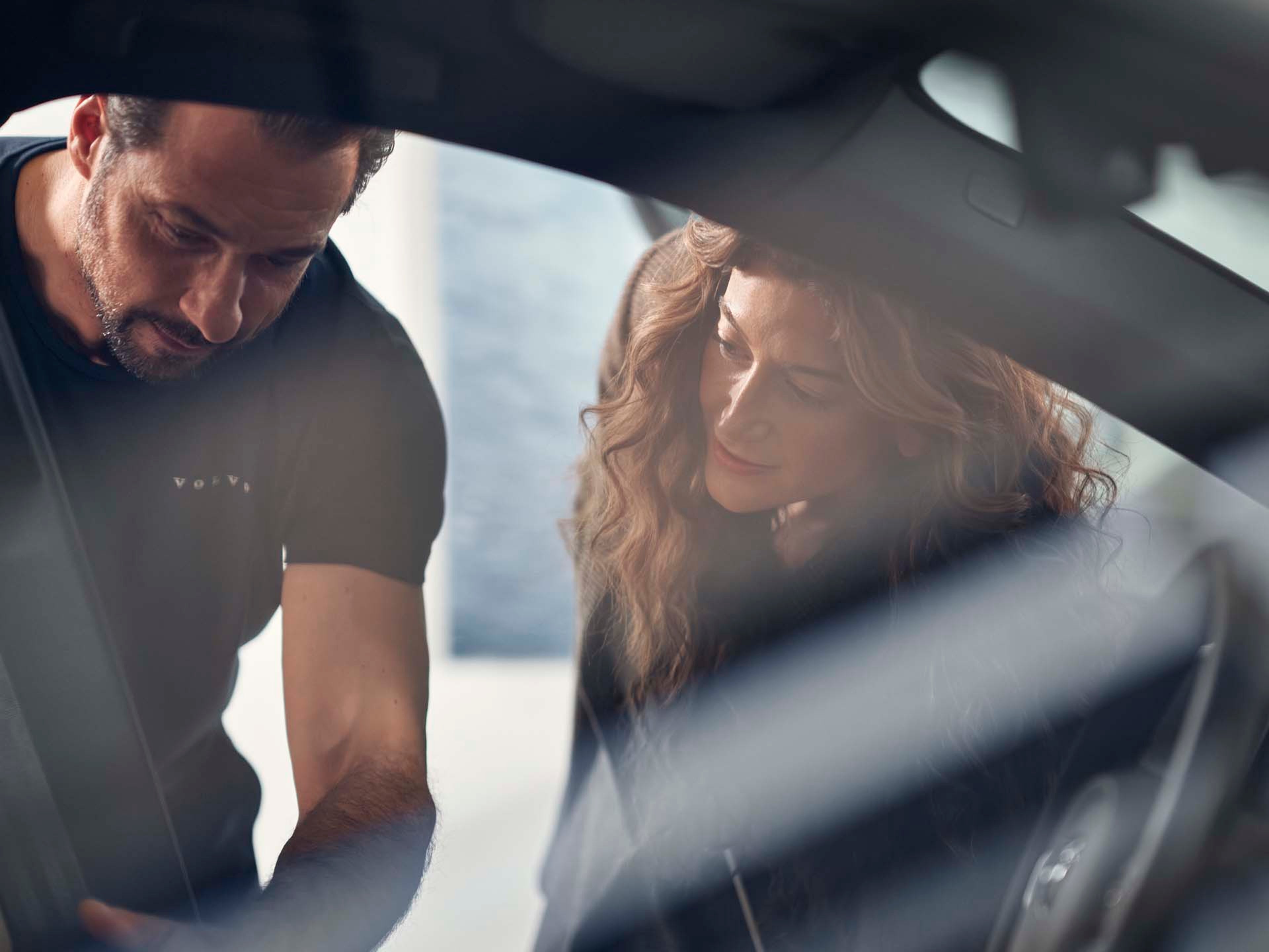 Un especialista de un concesionario Volvo mostrando el interior de un vehículo Volvo a una clienta.