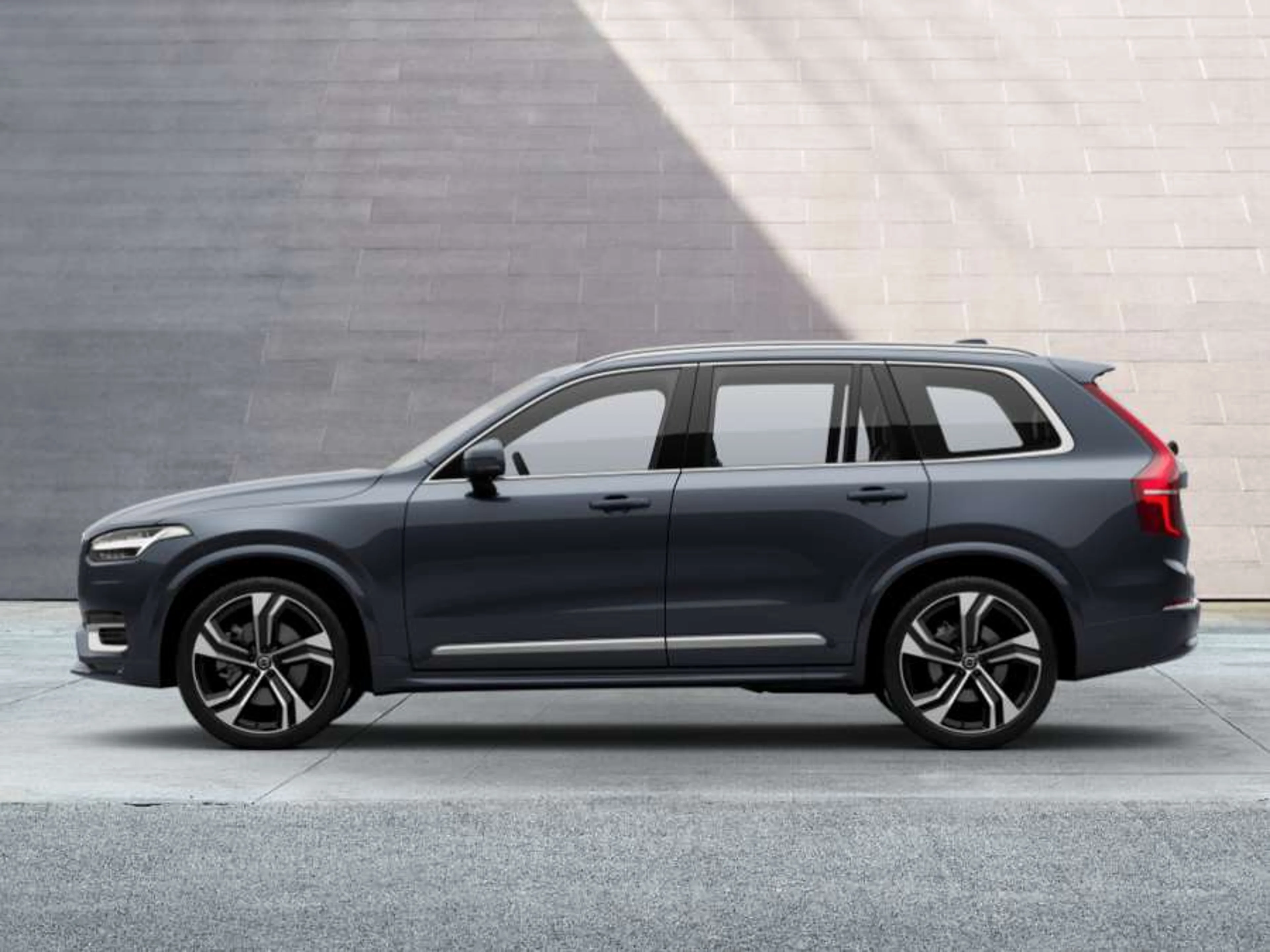 Volvo XC90 parkiran pred sivo steno, stranski pogled.
