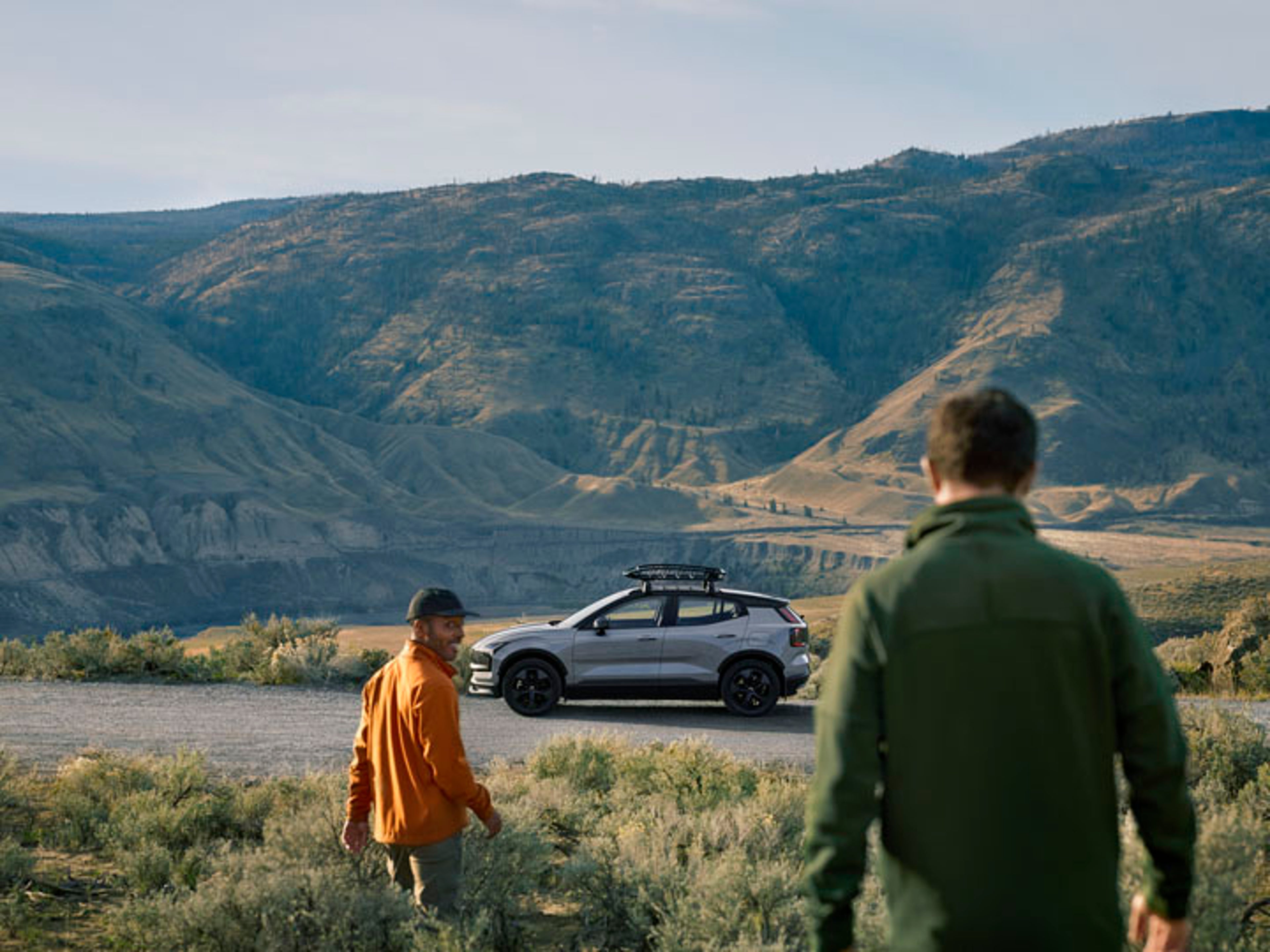 Dos hombres en medio del campo y un Volvo EX30 eléctrico en la carretera