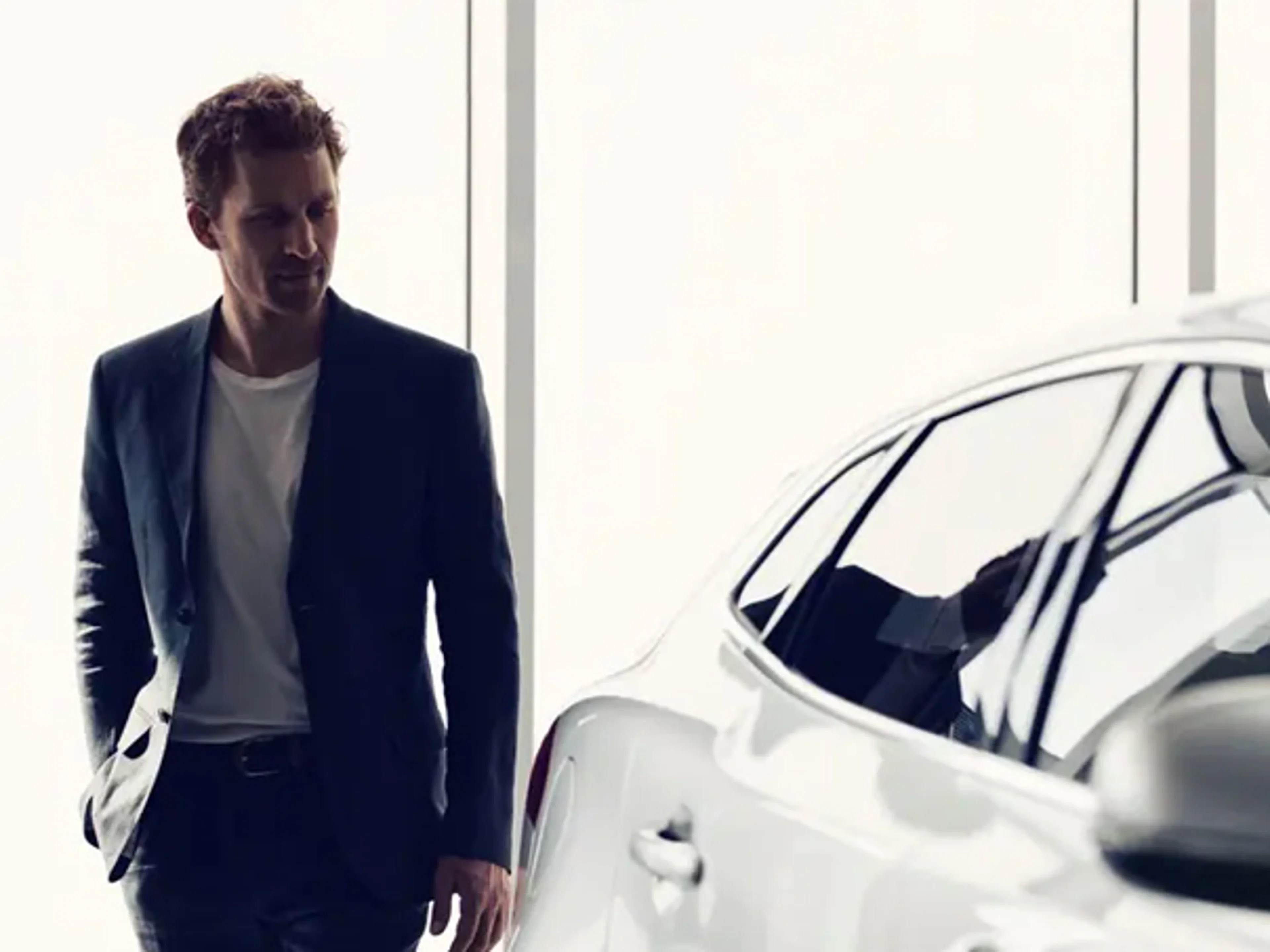 Mann i dress går rundt baksiden av en hvit Volvo