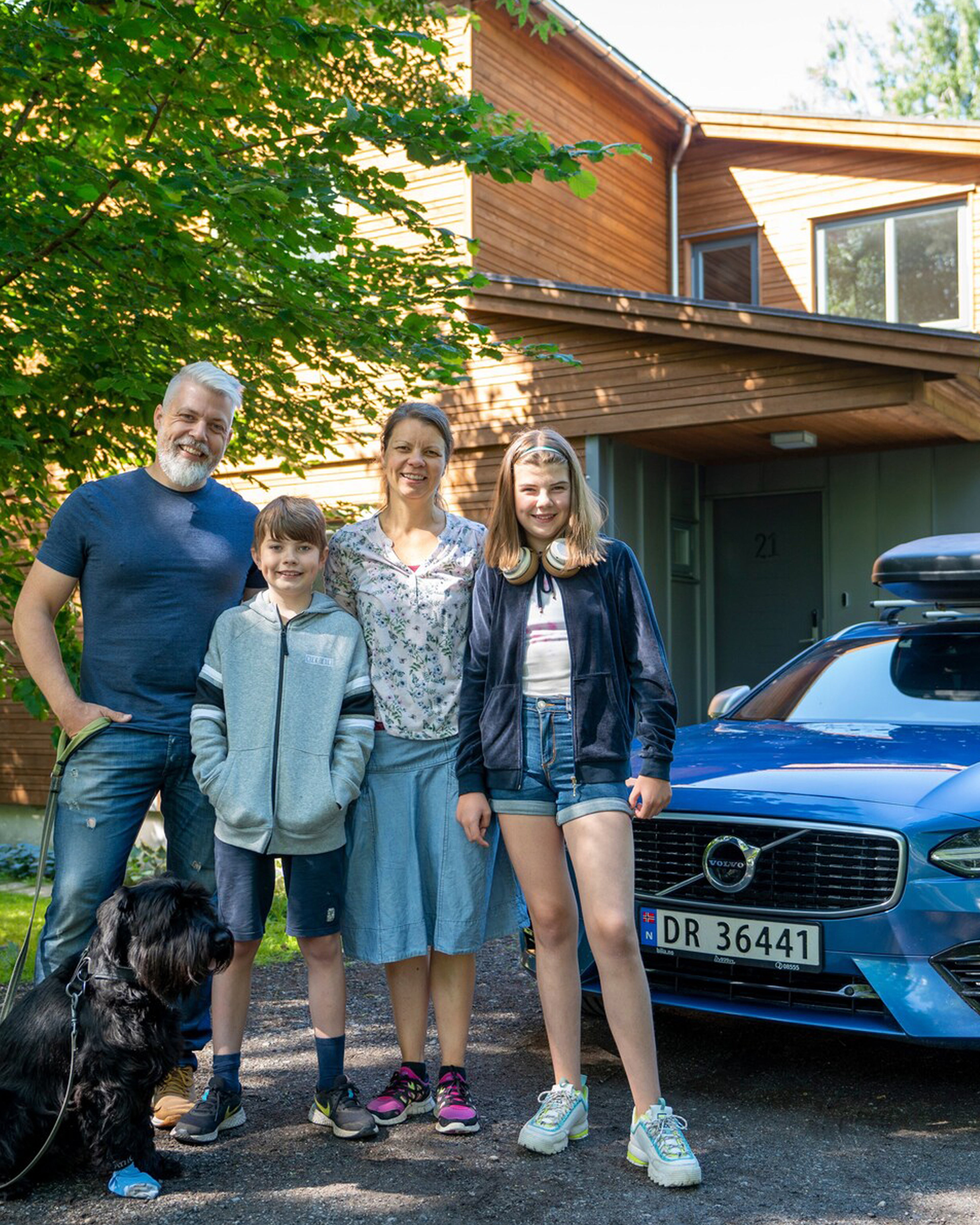Familie stående foran en blå Volvo