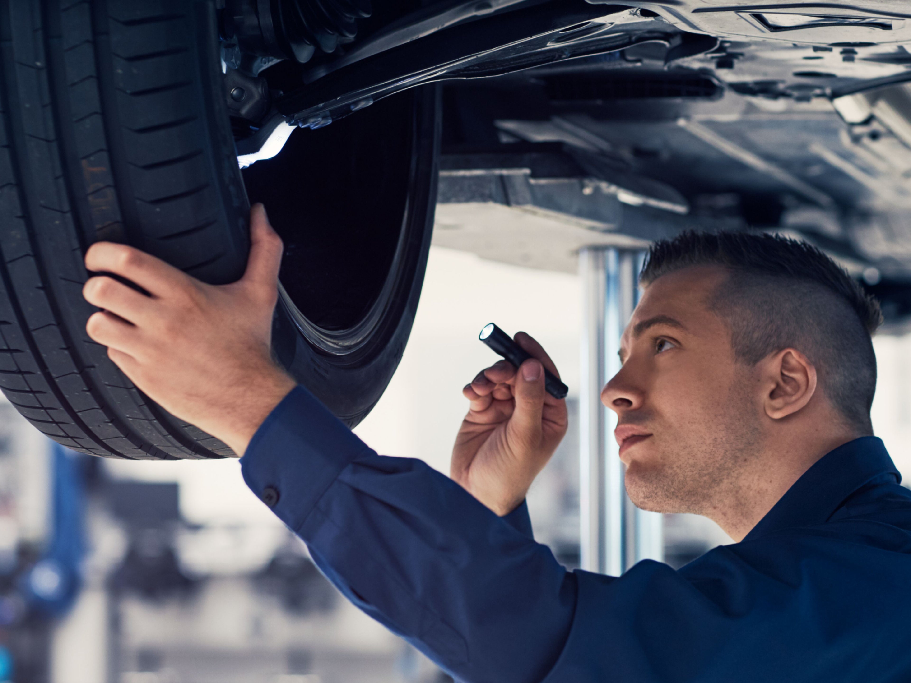 Ein Volvo Service Techniker prüft die Innenseite eines Rads von einem Volvo, der auf einer Hebebühne steht.