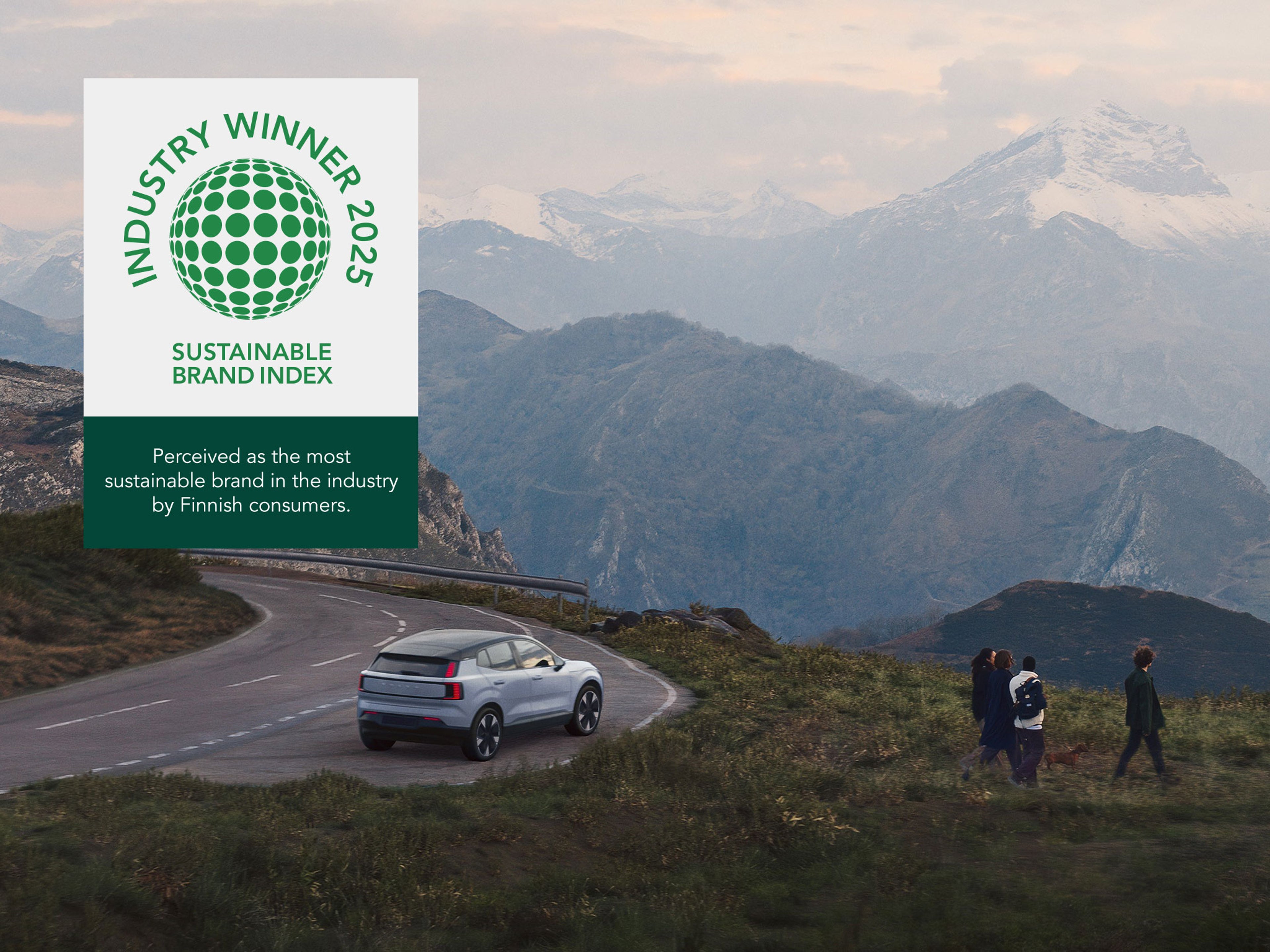 Logomerkki: Toimialan paras 2025 - Sustainable Brand Index. Koetaan toimialan vastuullisimpana brändinä kuluttajien keskuudessa. Taustalla kuva vuoristotien varteen pysäköity Cloud blue -värinen EX30 täyssähköauto ja neljä ihmistä ja mäyräkoira kävelemässä polulla.