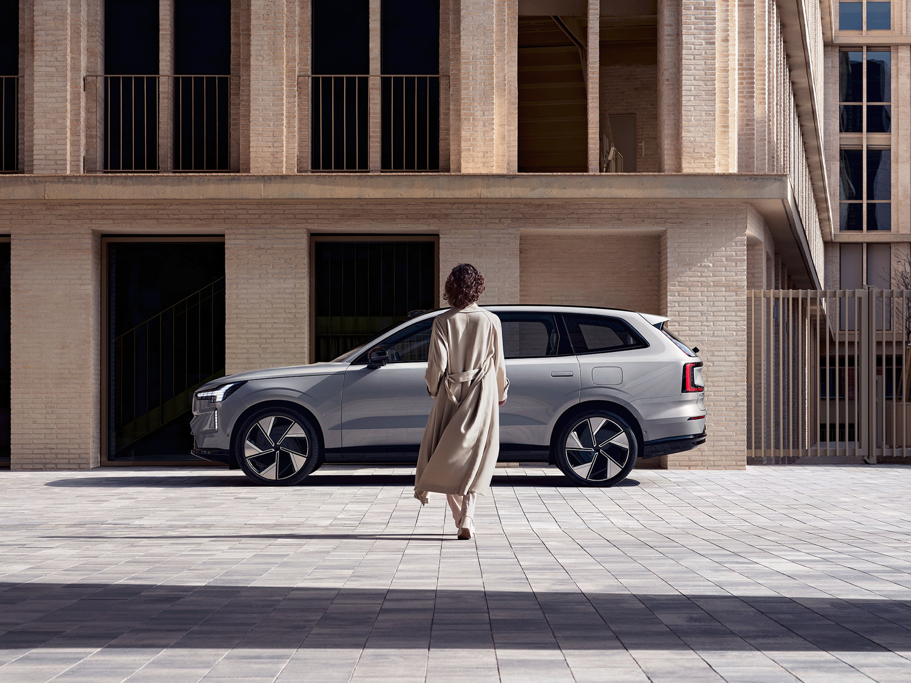 Eine Frau läuft auf einen Volvo EX90 zu.