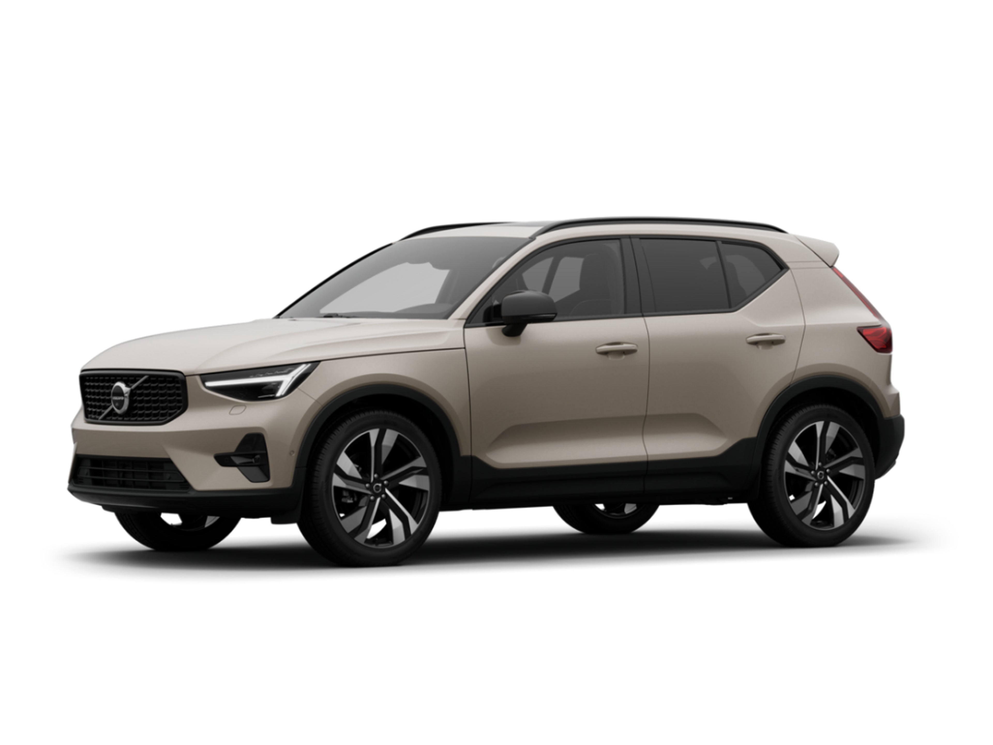 Kompaktni Volvo XC40 SUV u boji pijeska, parkiran u otvorenom krajoliku pod toplim svjetlom sumraka, ističući njegov prepoznatljiv i moderan dizajn.