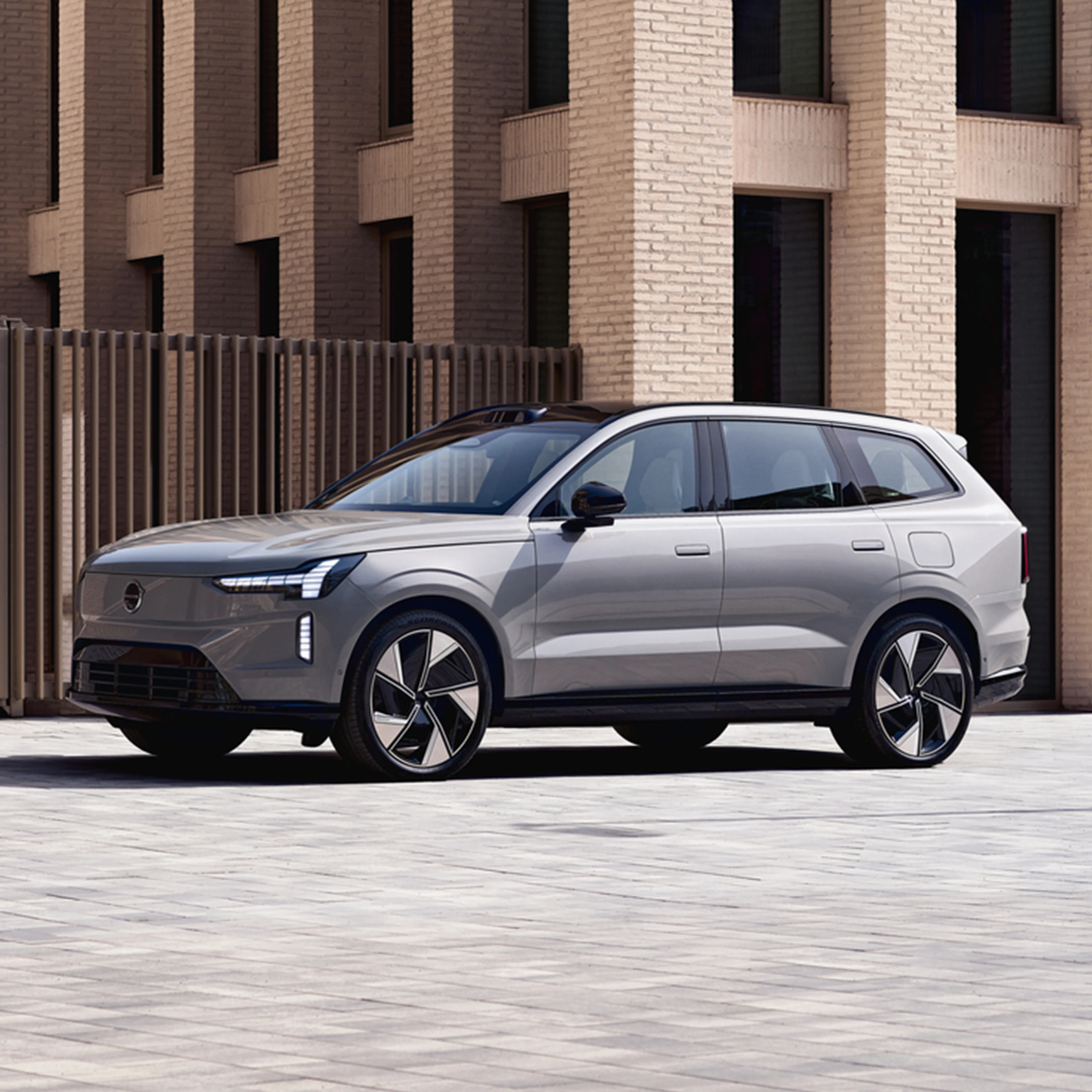 Vapour Grey -värinen Volvo EX90 täyssähköauto pysäköitynä kaupunkipihaan.