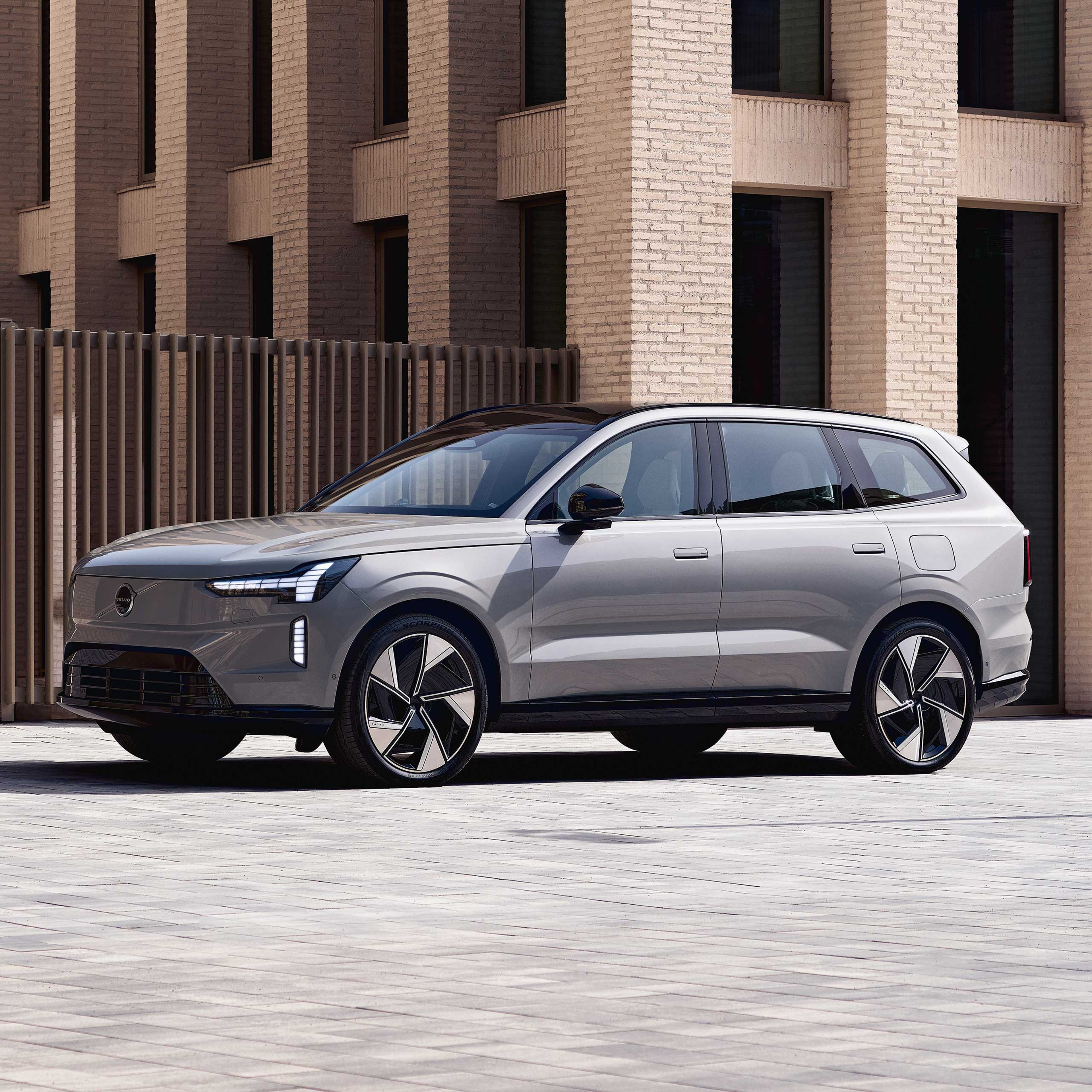 Vapour Grey -värinen Volvo EX90 täyssähköauto pysäköitynä kaupunkipihaan.