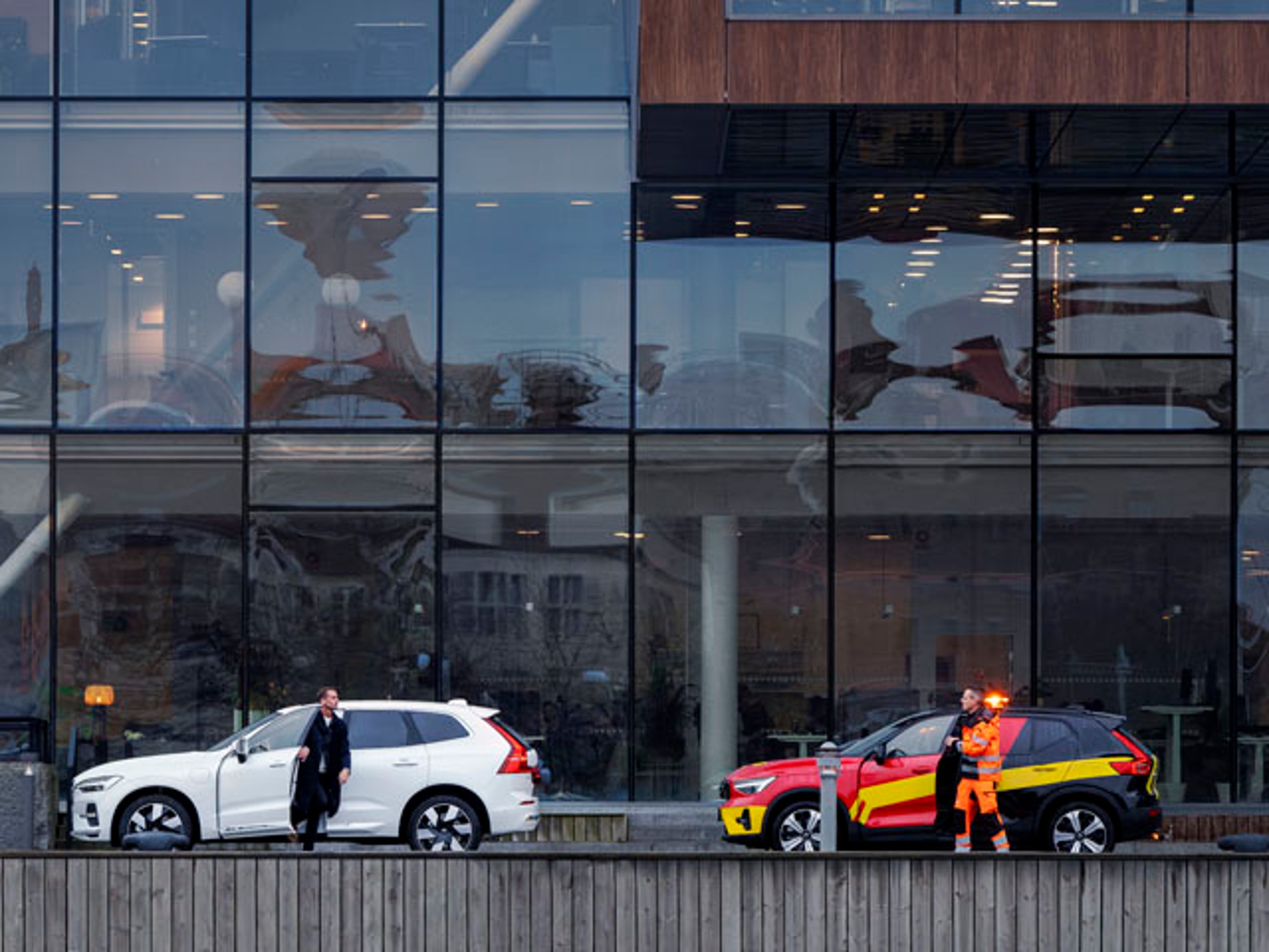 Un hombre recibiendo la ayuda de Volvo Assistance delante de un edificio acristalado.