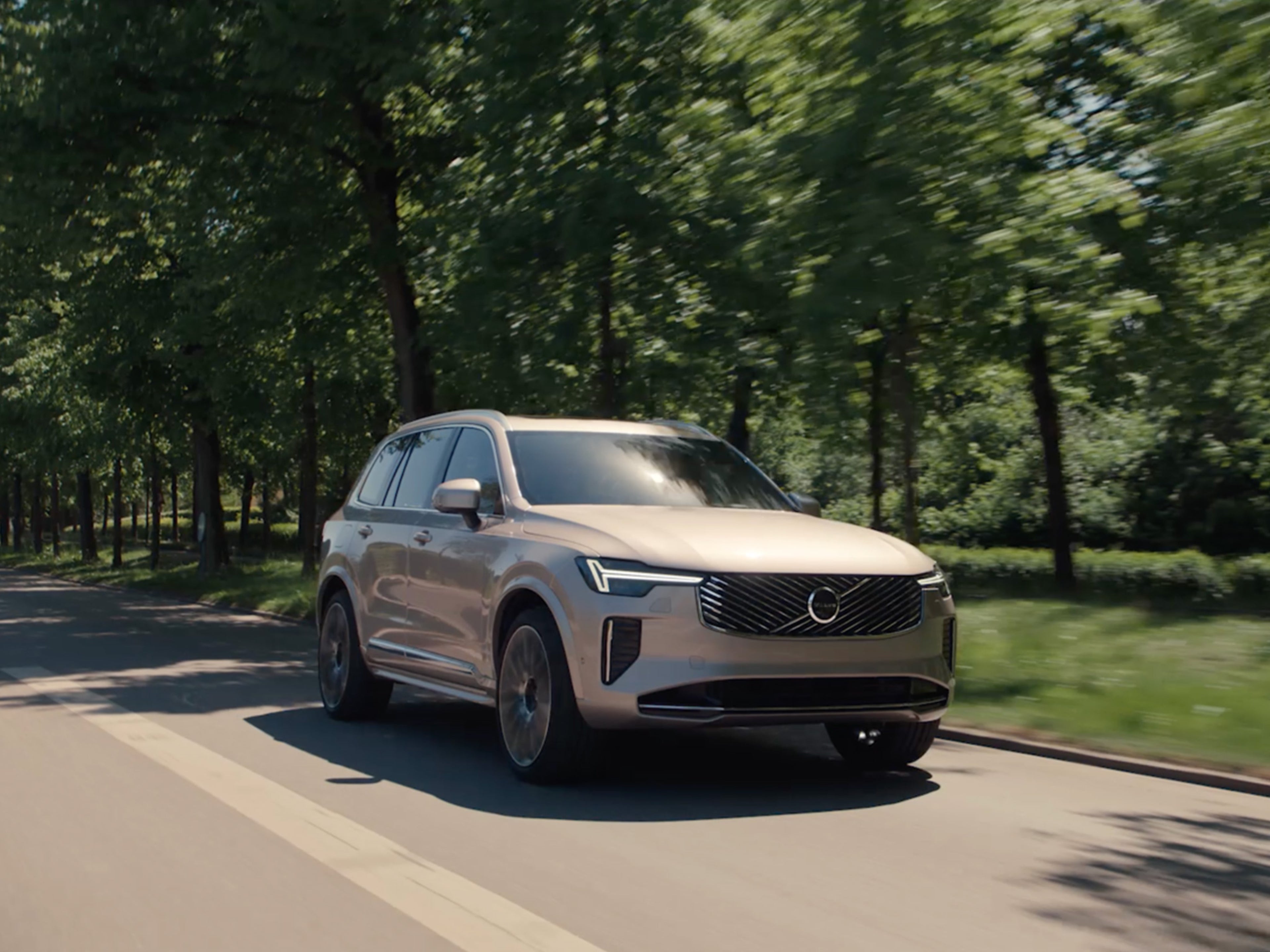 Volvo XC90 lataushybridikatumaasturi ajelulla. Taustalla lehtipuita