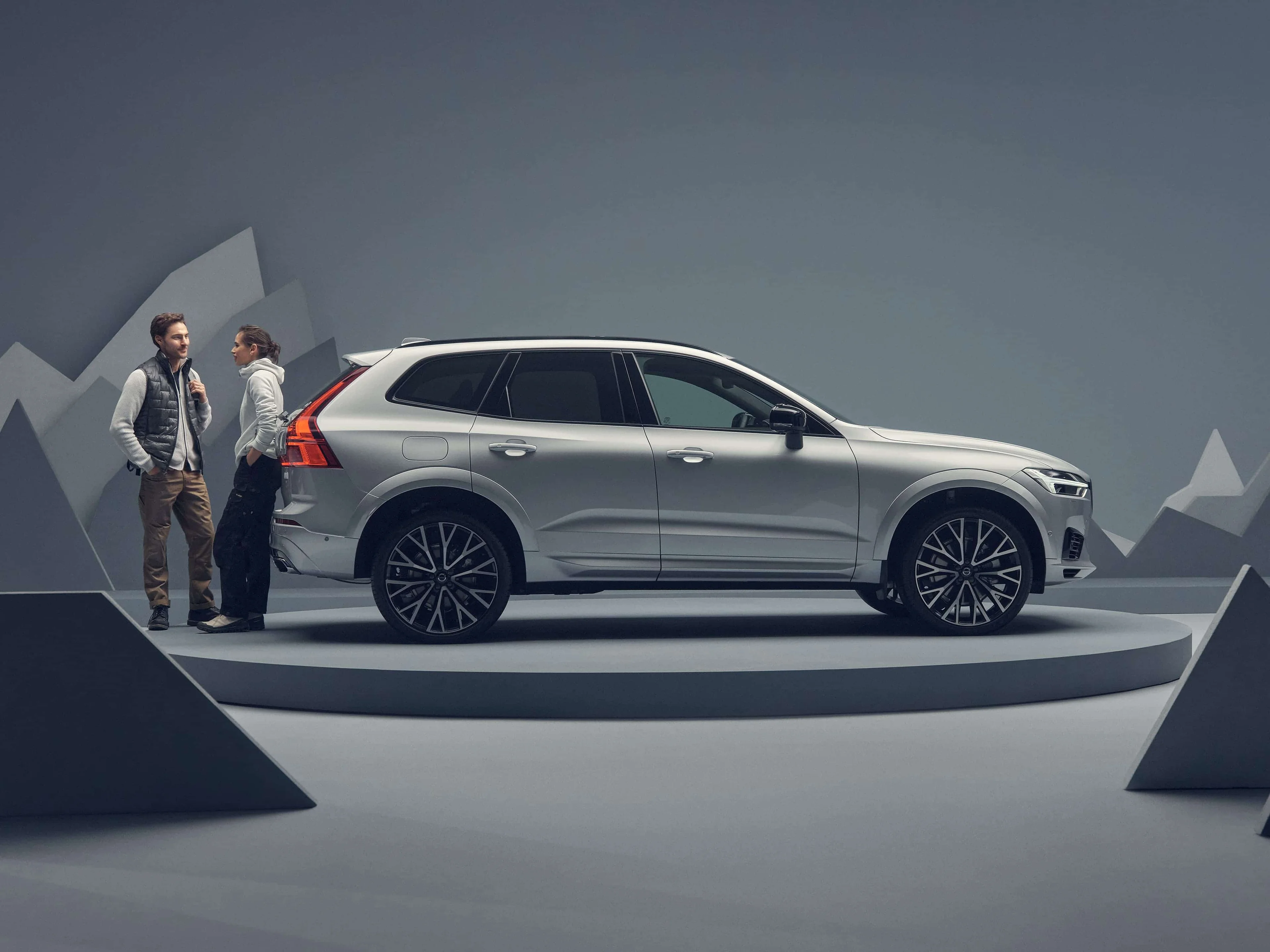 Un couple se tient à côté d'un Volvo XC60 argenté sur une plateforme.