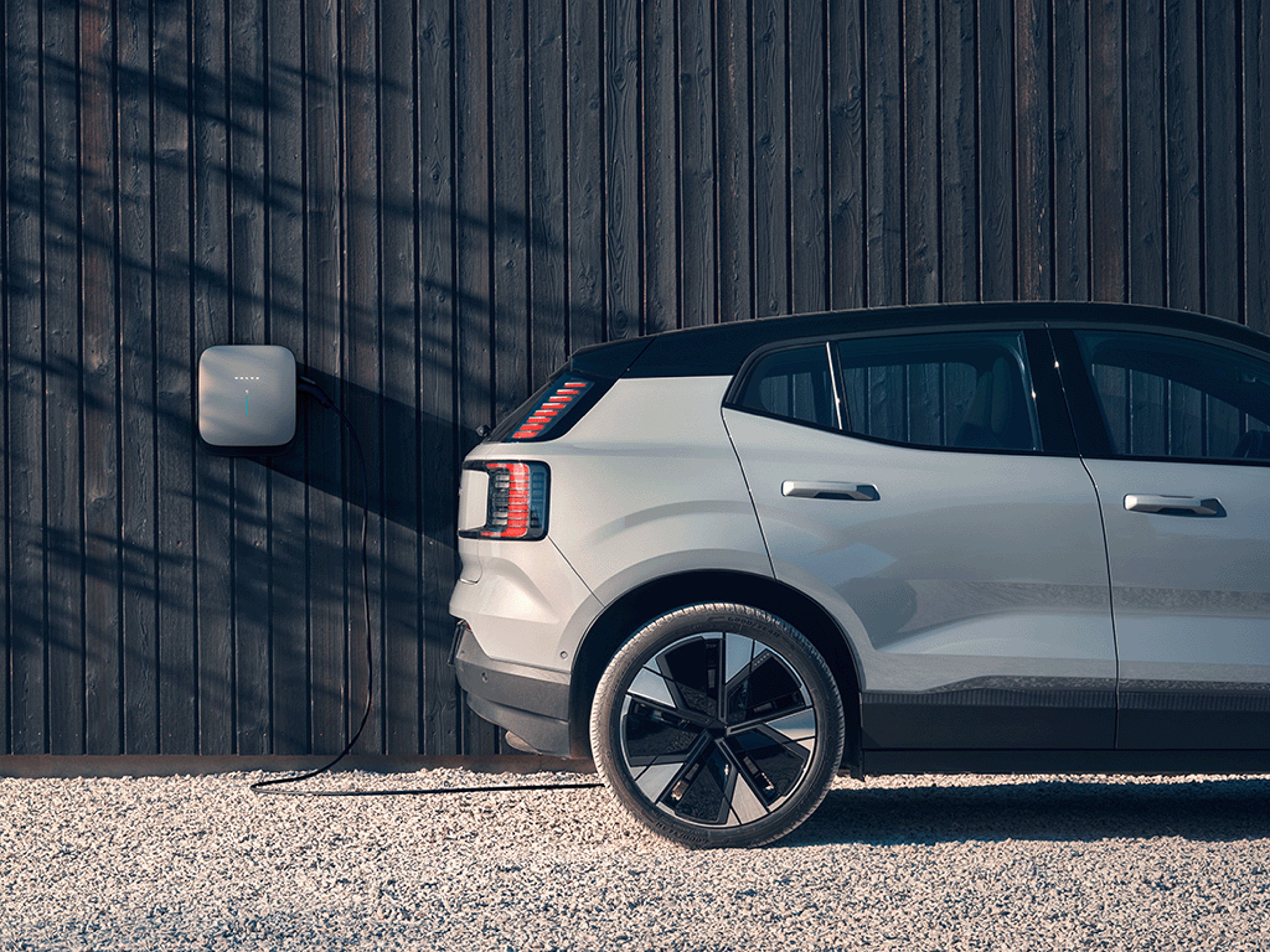 Seitliche Heckansicht eines Volvo EX30 an einer Volvo Wallbox.