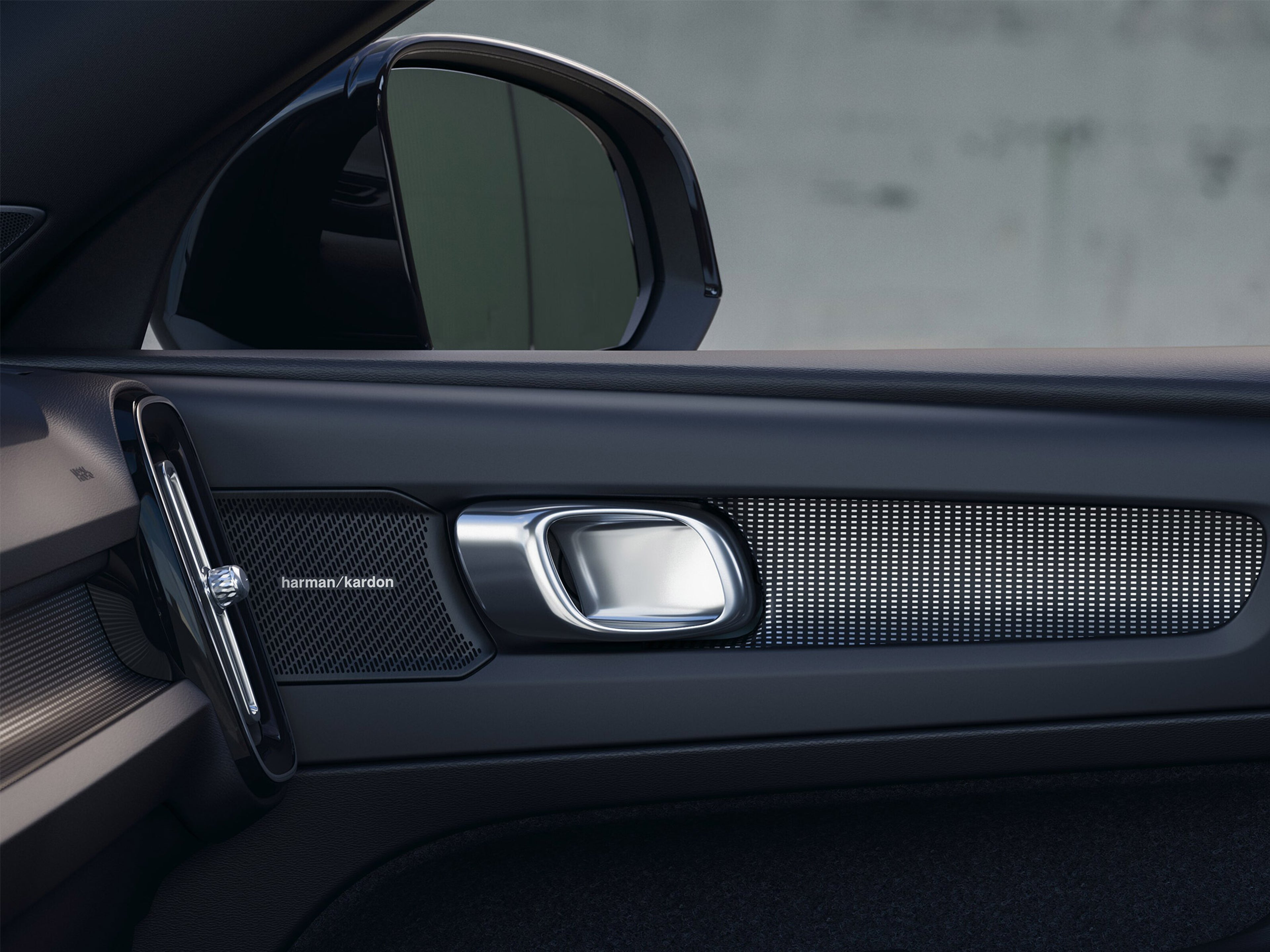 Yksityiskohta Volvo EX40 täyssähköauton matkustajan puoleisesta etuovesta, jossa näkyy oveen kiinnitetty Harman/Kardon kaiutin.