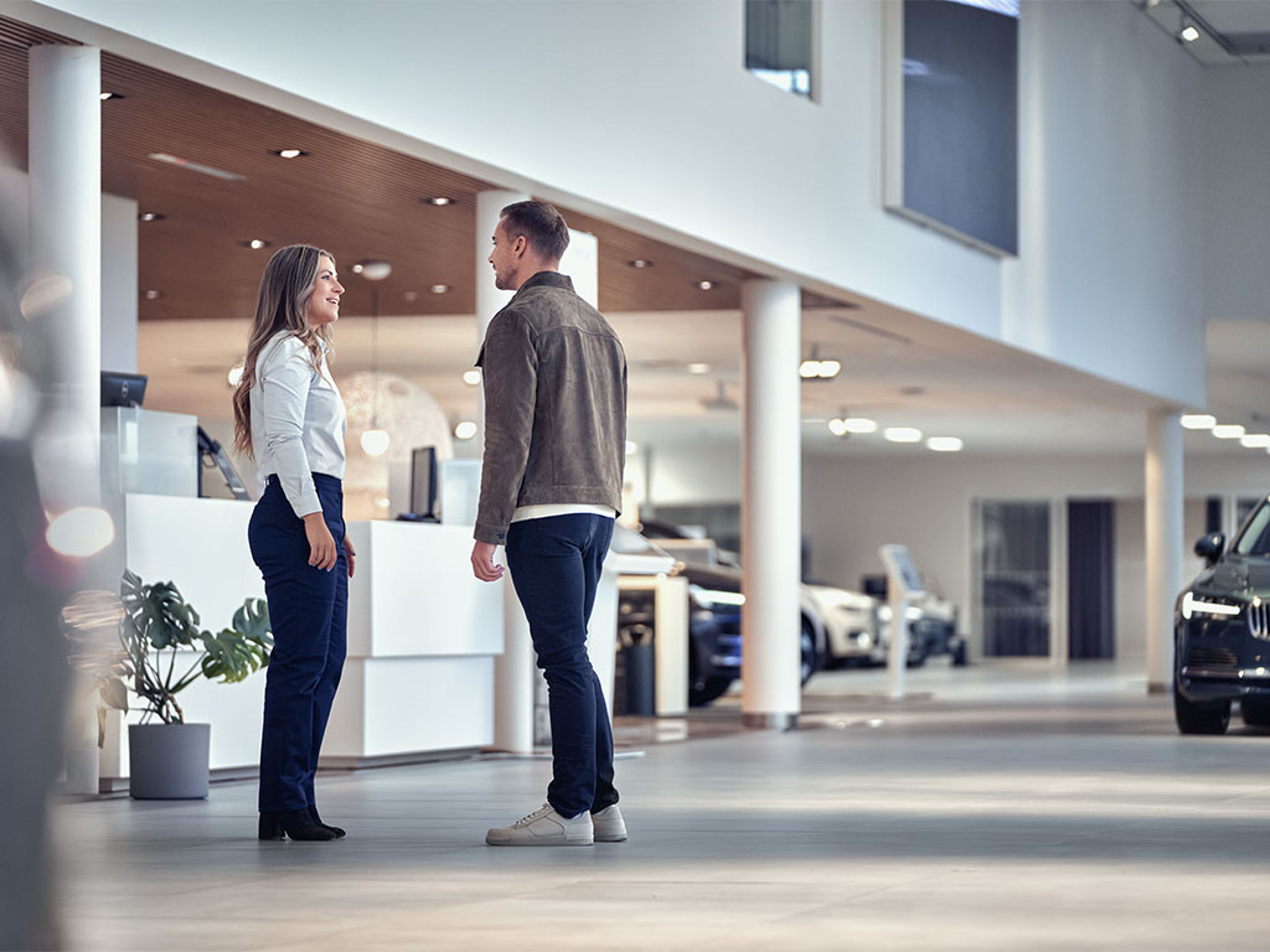 Un client discute avec un conseiller dans une concession Volvo moderne avec des voitures en arrière plan