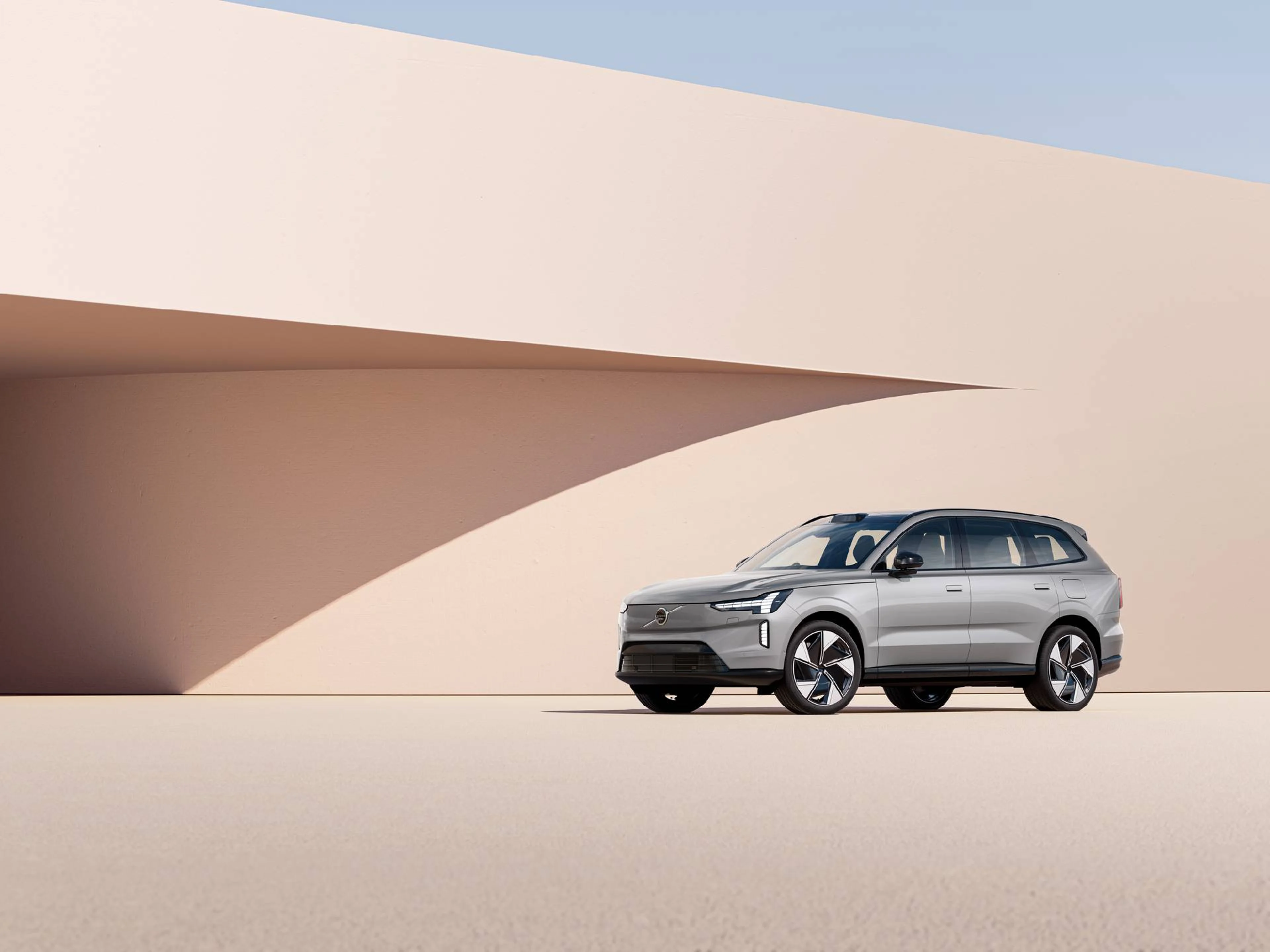 Un Volvo EX90 eléctrico color plateado entre dunas destacando sus luces LED con forma de martillo de Thor