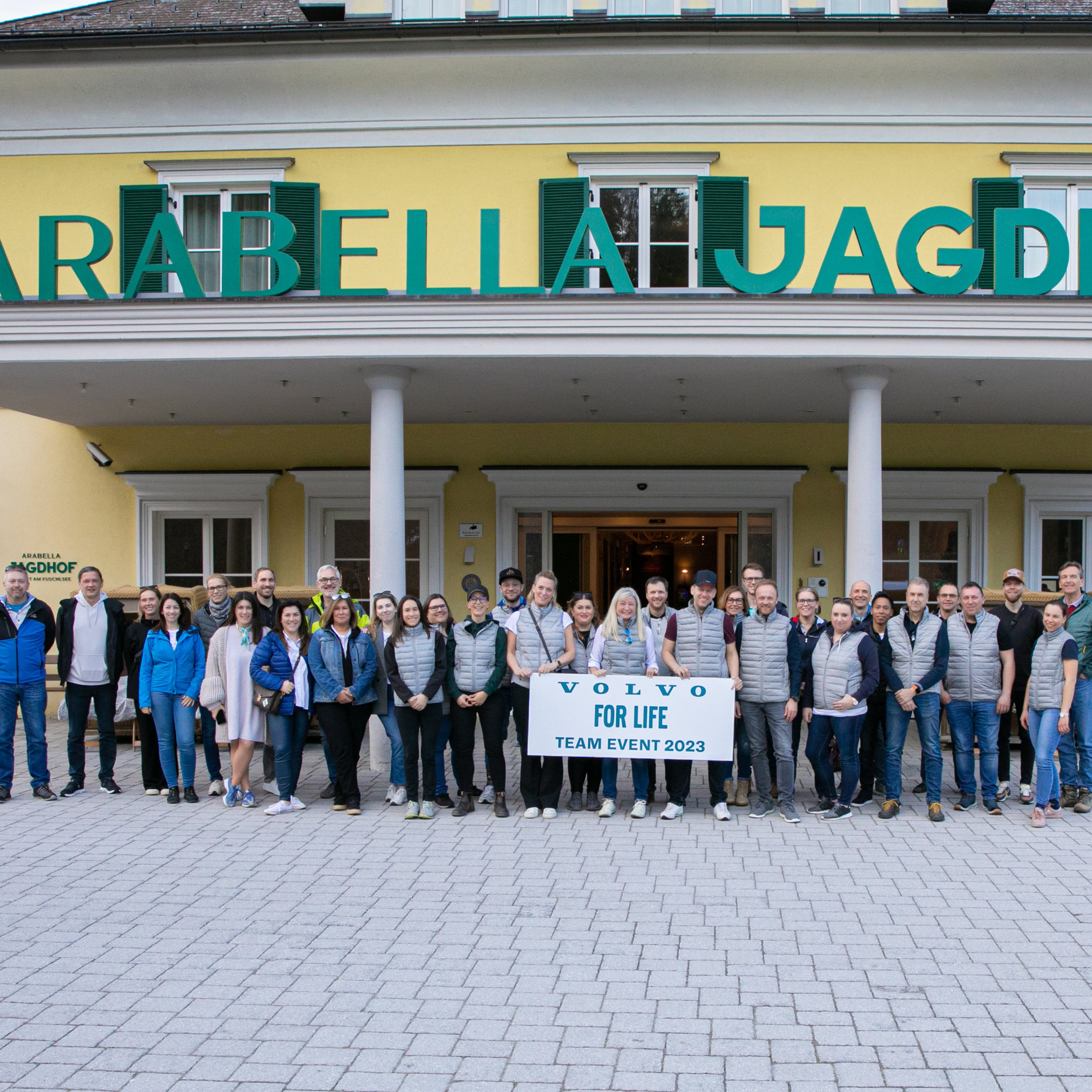 Volvo Car Austria Team posiert für ein Foto mit einem Schild "Volvo For Life Team Event 2023"