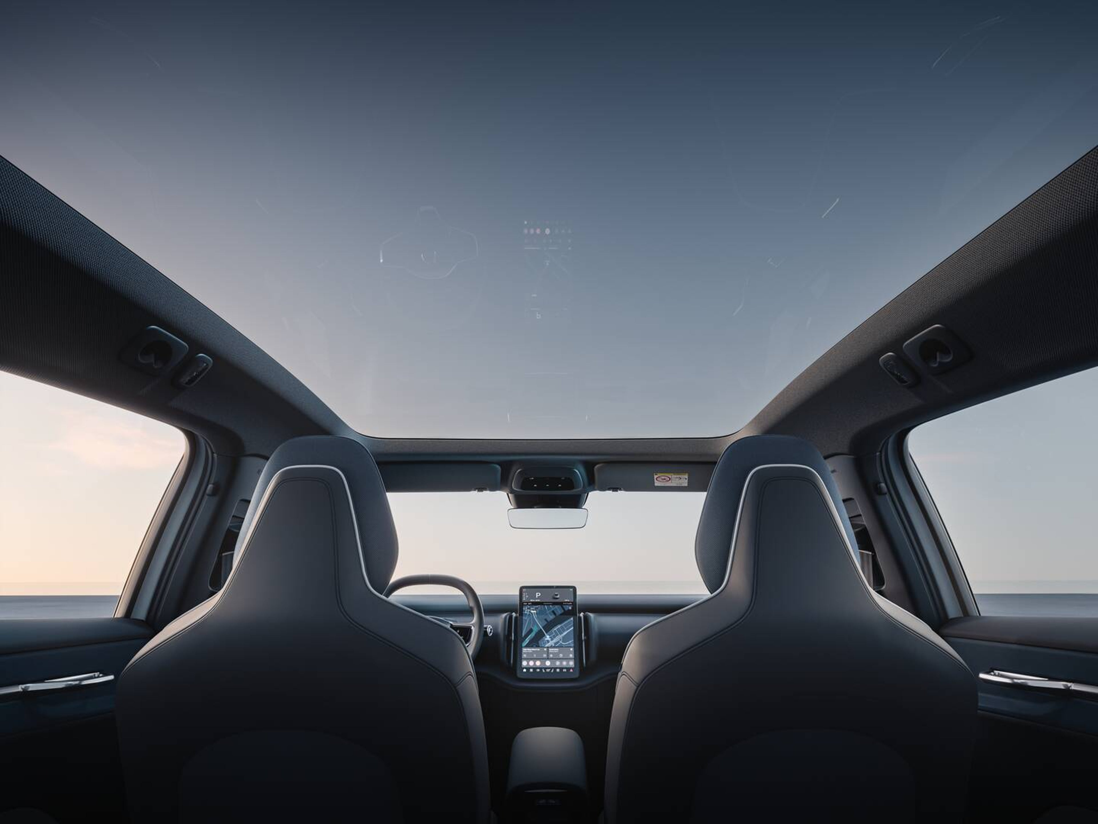 Mørke forsæder og midterskærmen i en Volvo bil ses fra midten af bagsædet.