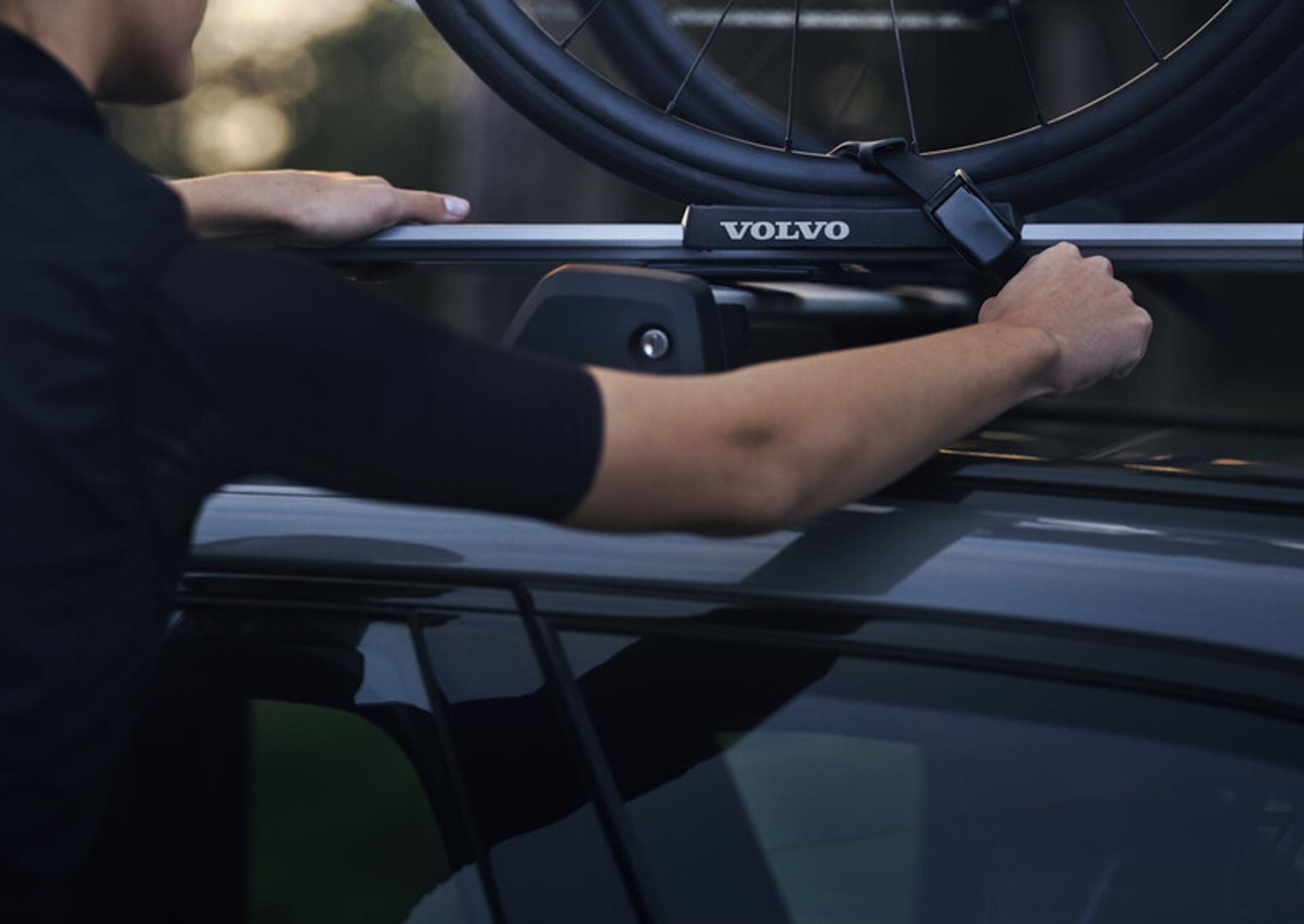 Mężczyzna mocujący rower na dachu Volvo używający akcesoriów Volvo
