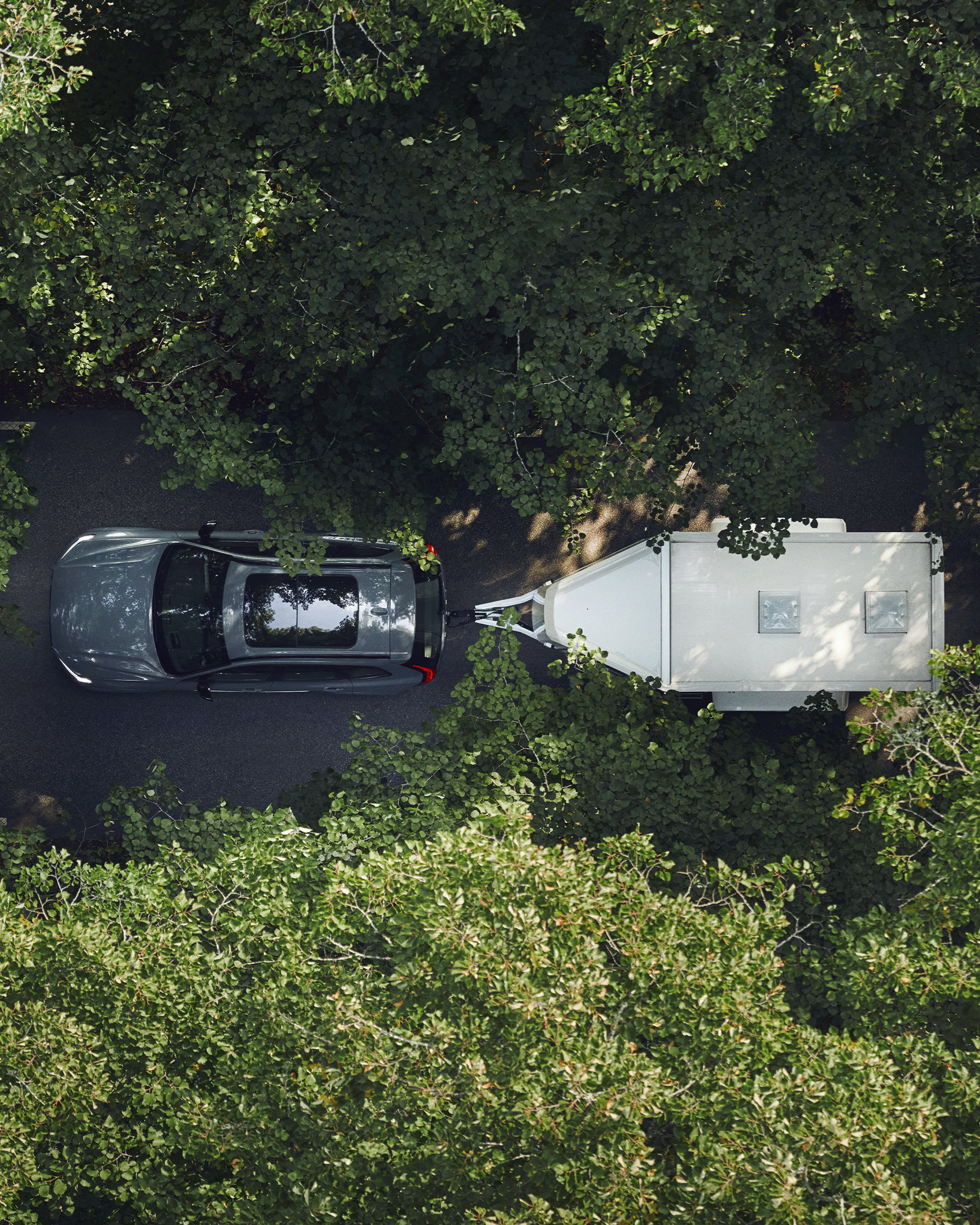 Un vehículo Volvo remolcando un bote en medio de un terreno boscoso.