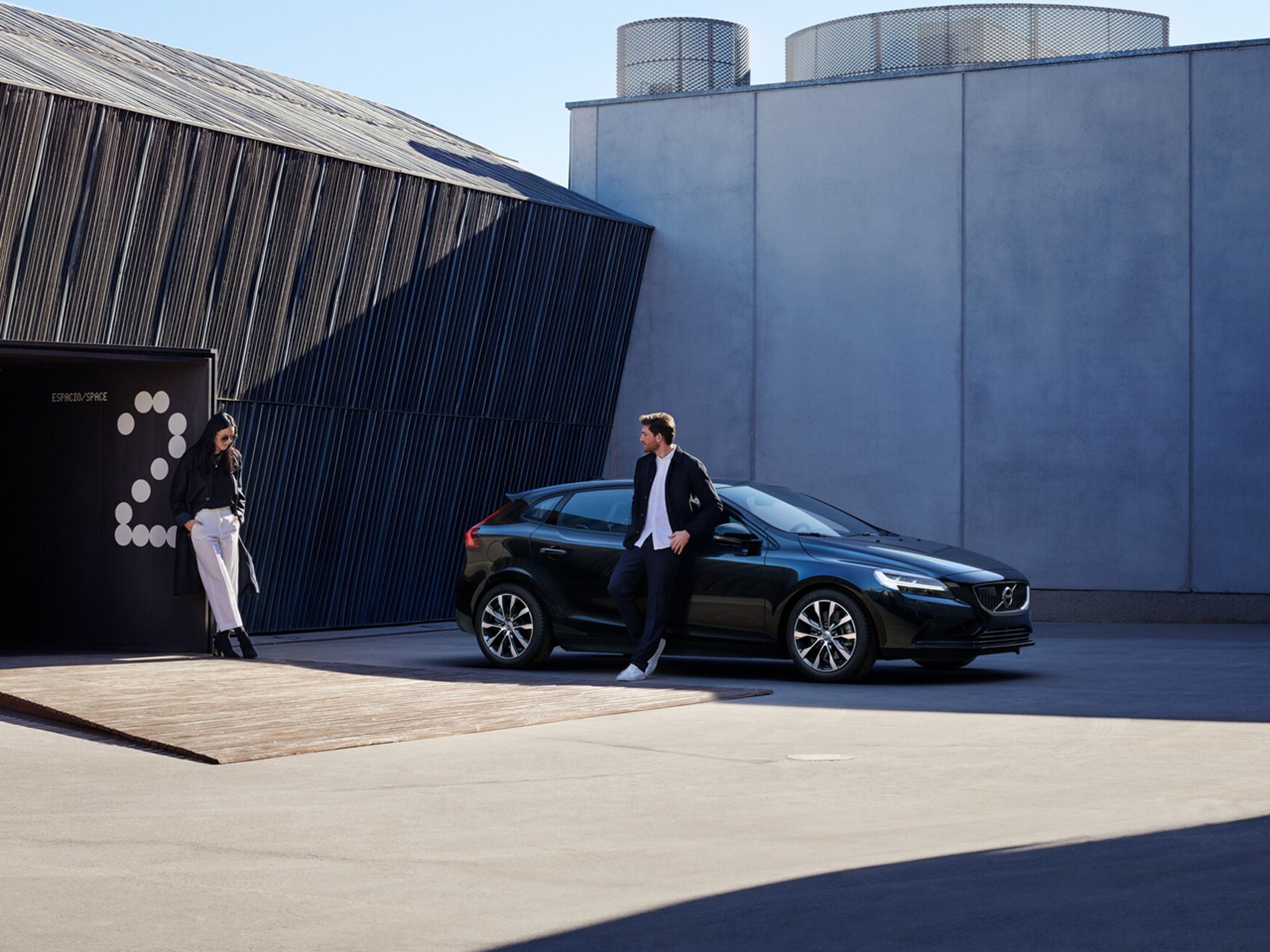 Mann lener seg på en parkert Volvo