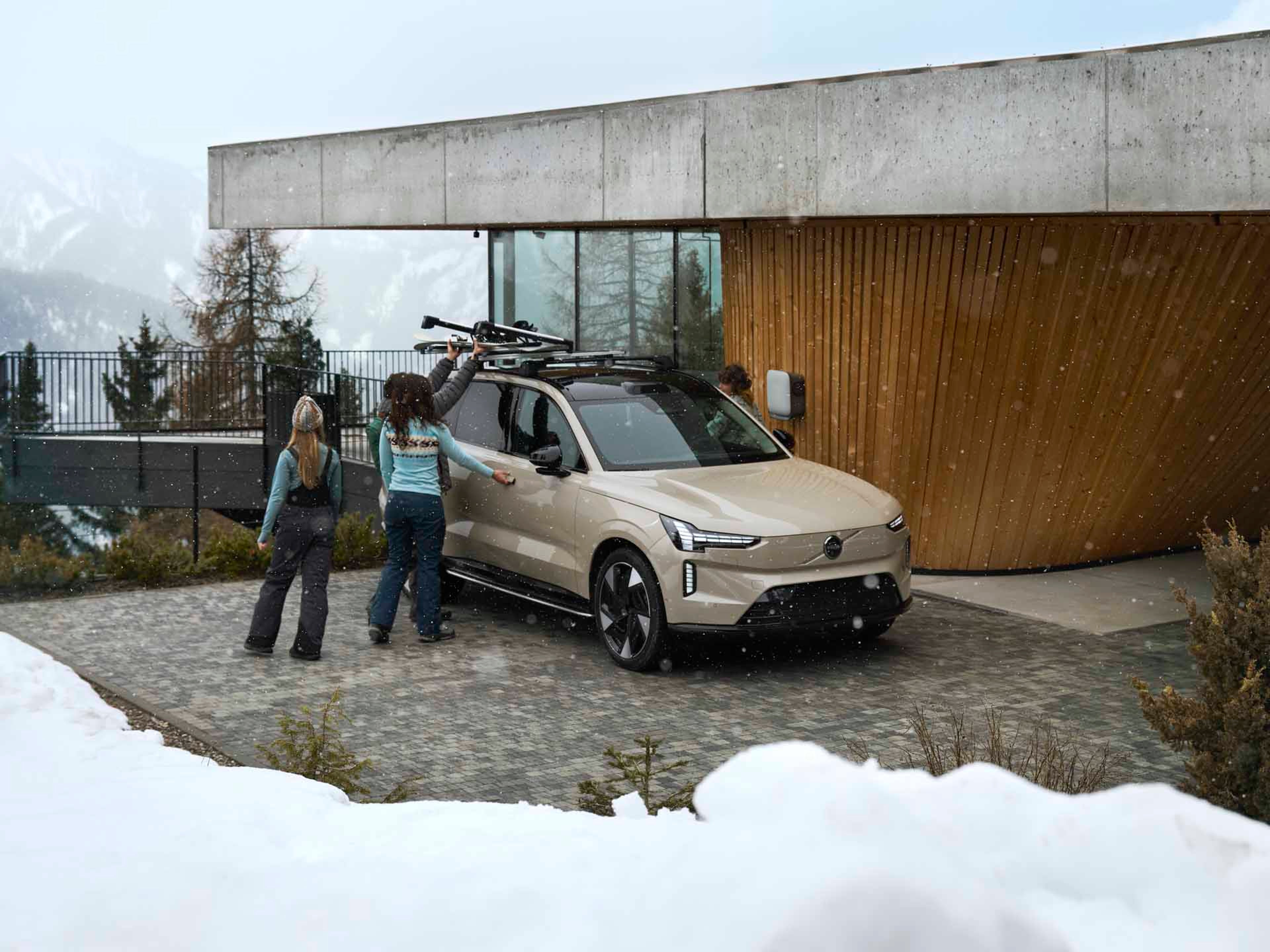 Un Volvo eléctrico con accesorios de invierno y rodeado de montañas nevadas