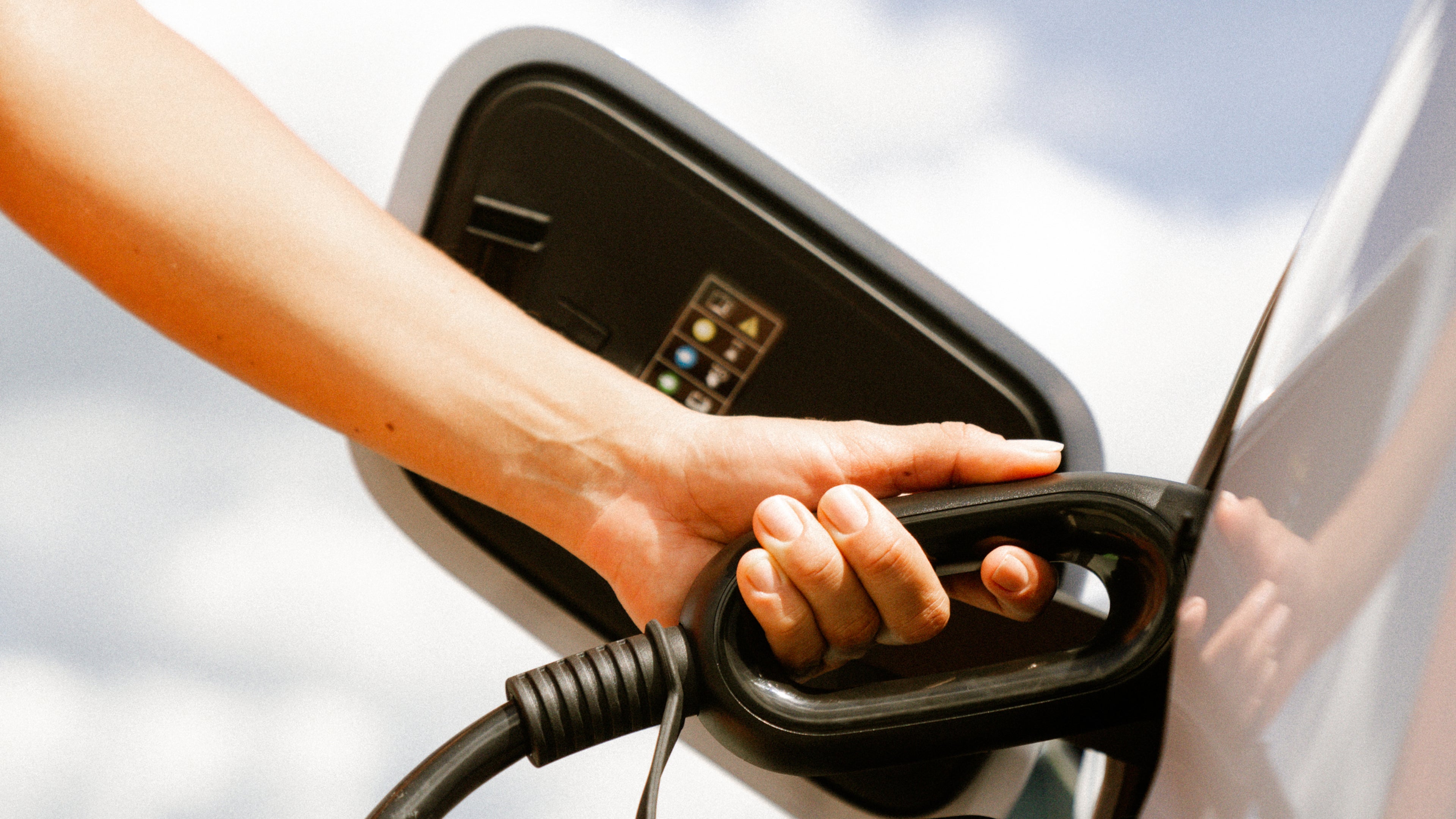 Aufnahme einer Hand, die einen Tankschlauch hält und ein Fahrzeug betankt.