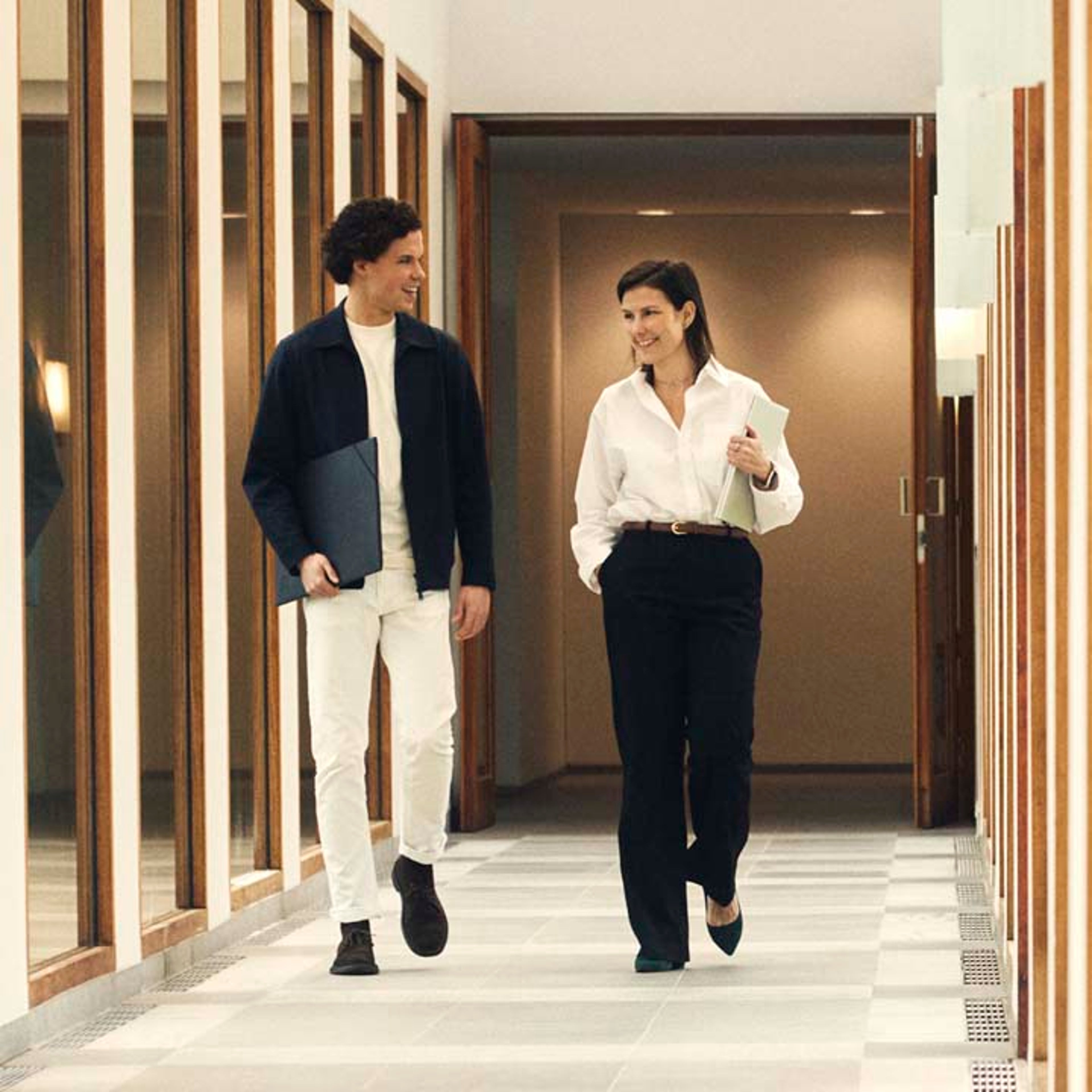 Un hombre y una mujer operadores independientes caminando por un pasillo de unas oficinas Volvo