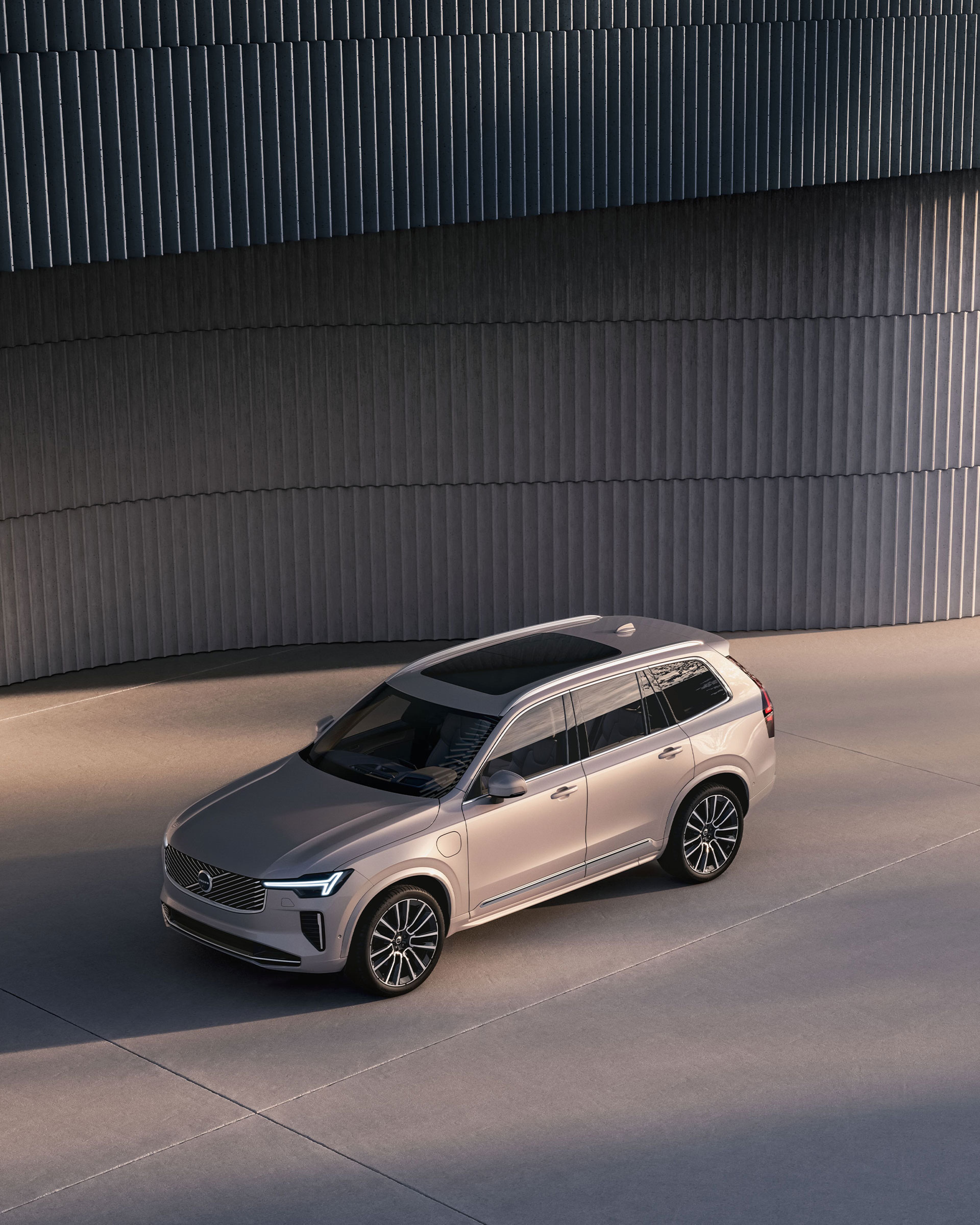 Ein Volvo XC90 in der Farbe Denim Blue steht seitlich in einem Studio