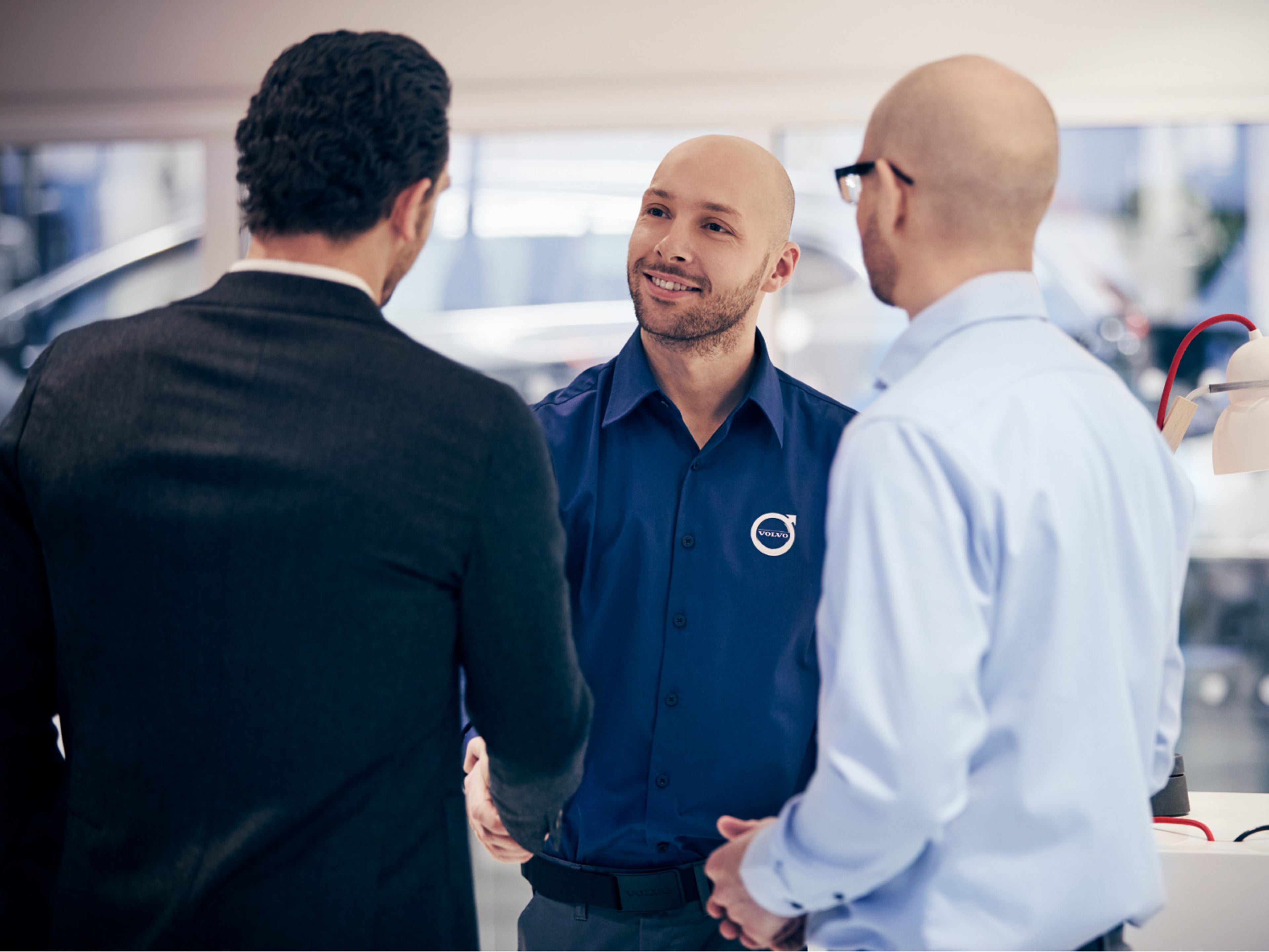 Un expert Volvo serre la main d'un client dans la salle d'exposition.