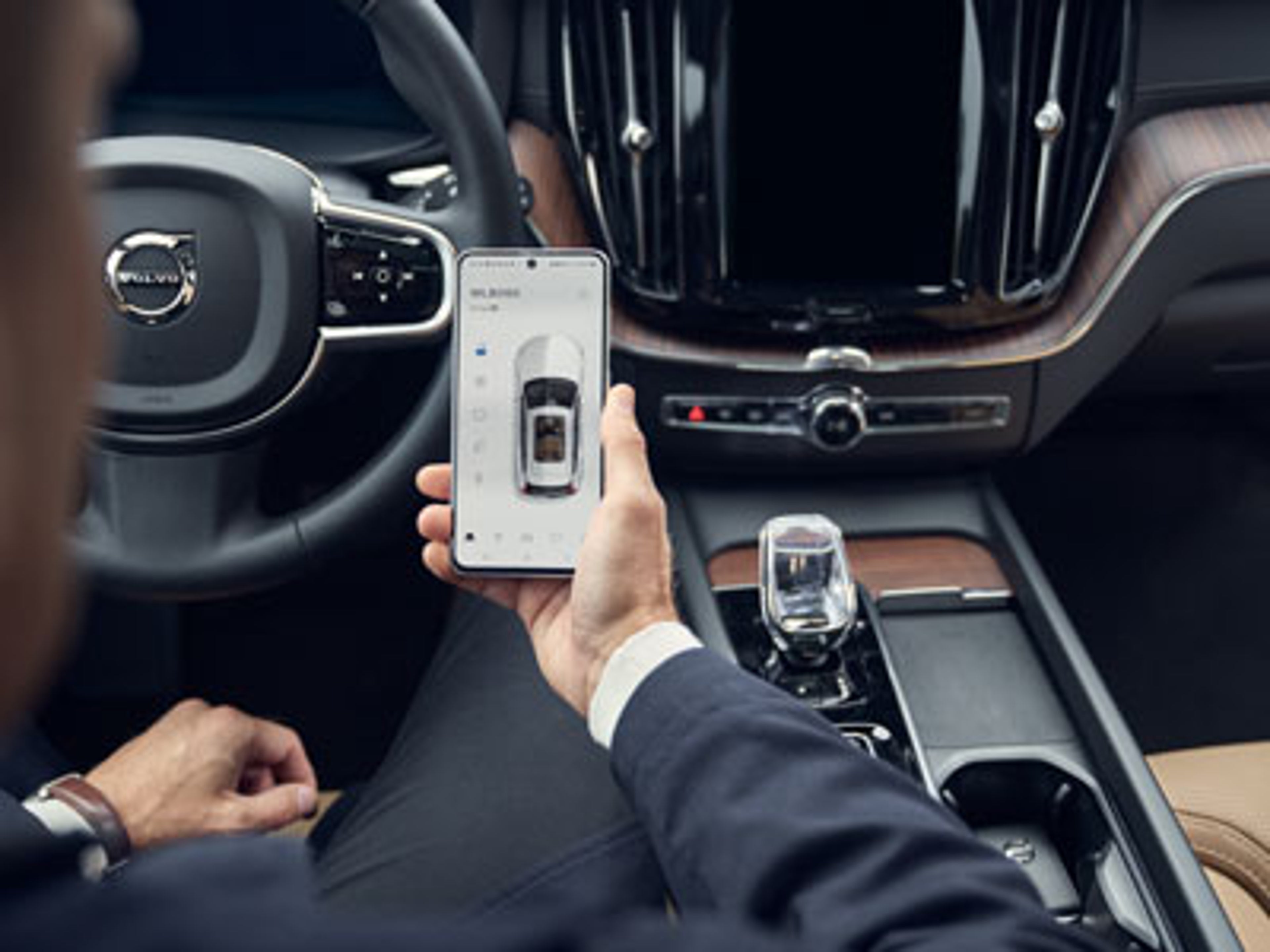 En som sitter i førersetet og ser Volvo Cars-appen på telefon