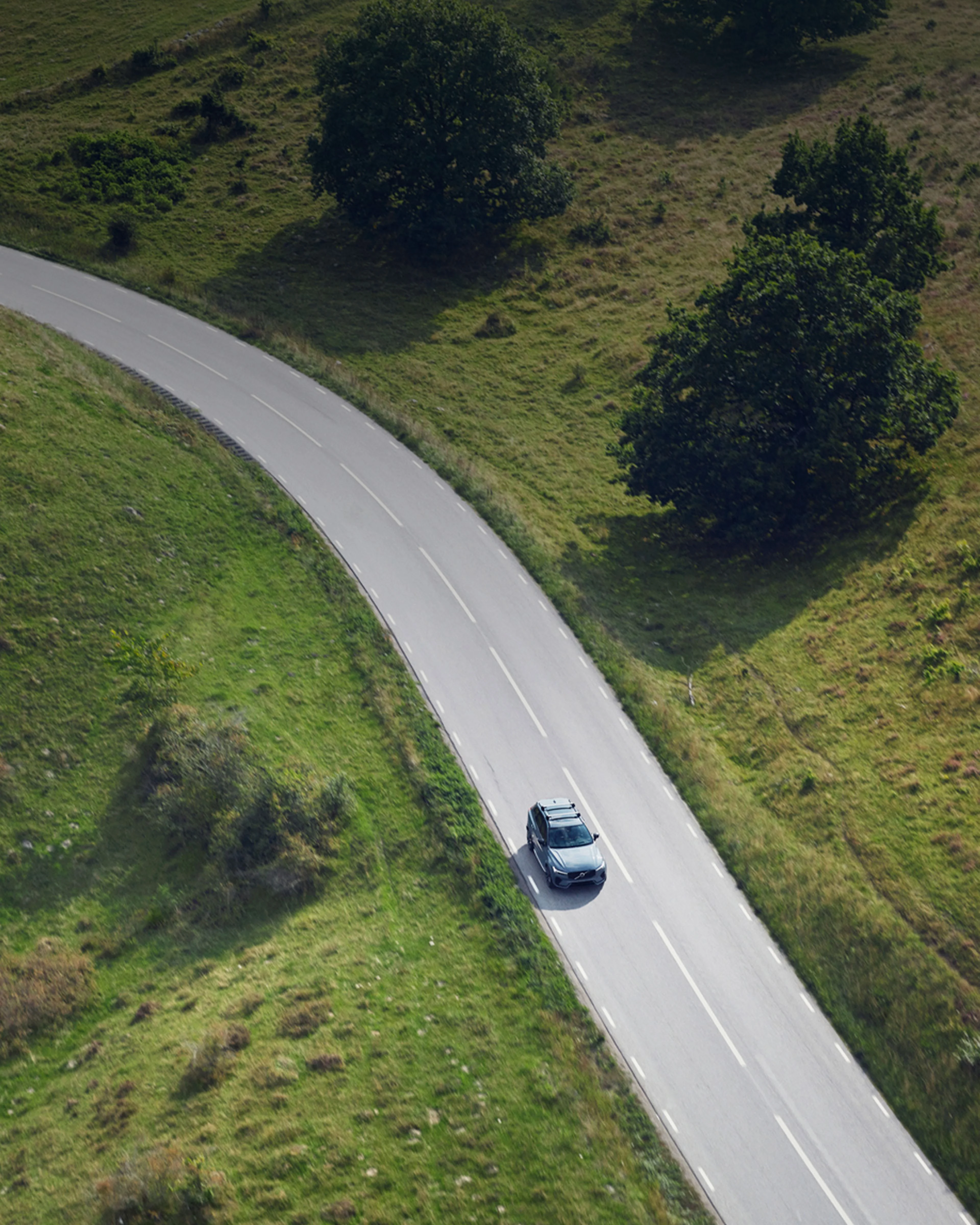 Volvo XC60 descendiendo una colina con prados verdes a los costados