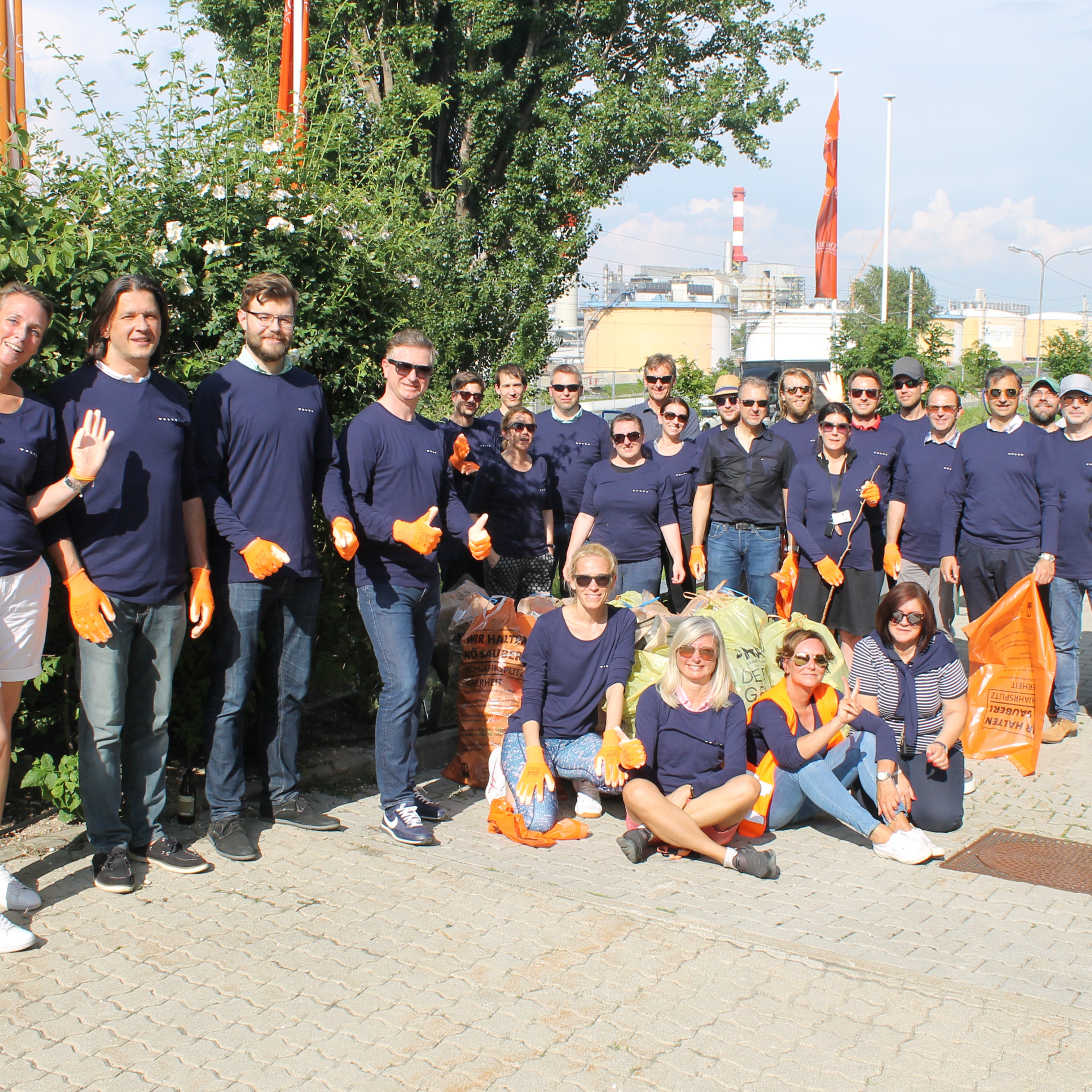 Volvo Car Austria Team in dunkelblauen Shirts mit Volvo Logo rechts oben. Sie sind beim Teamevent und sammeln Müll auf