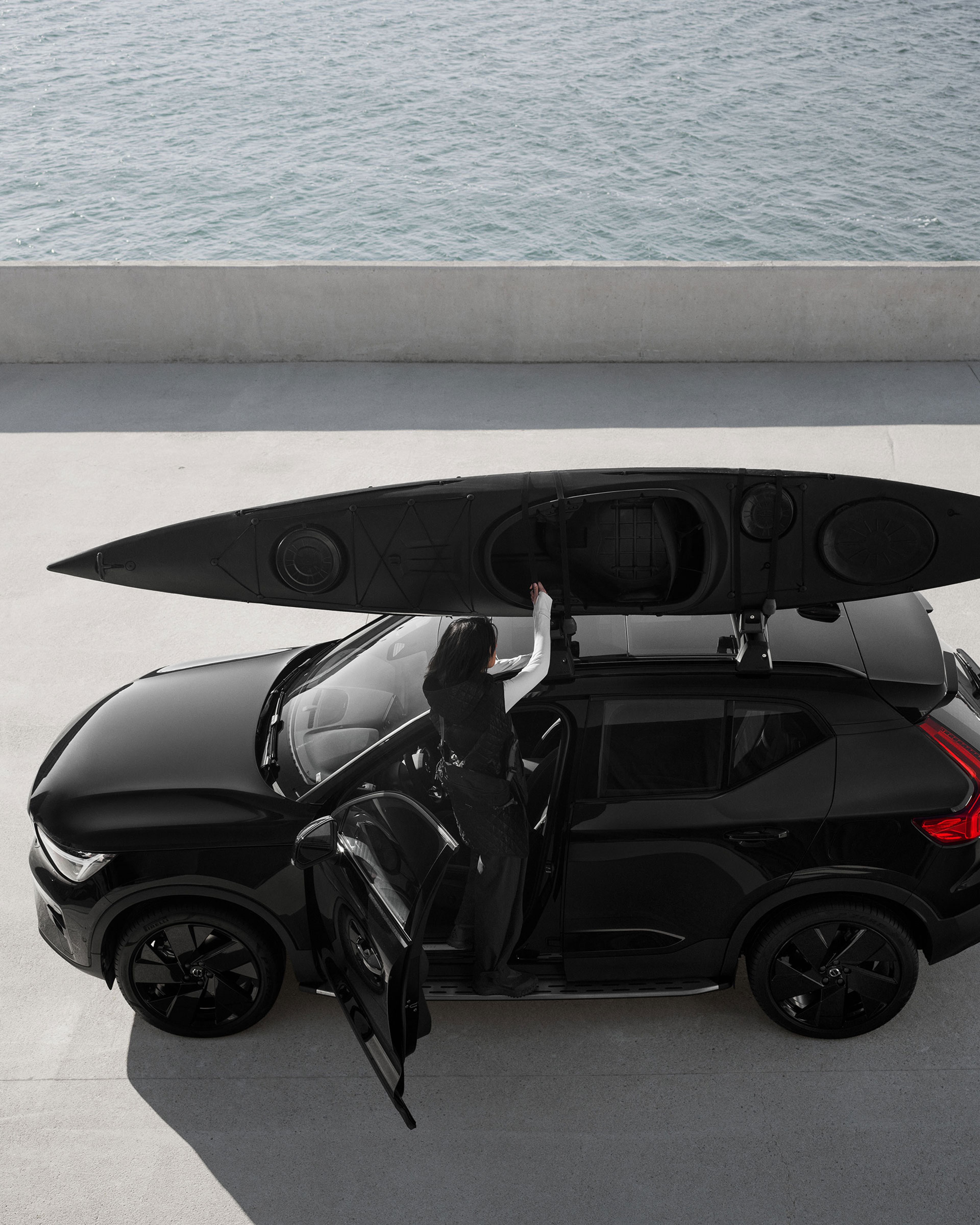 EX40 Black Edition vu de côté sur un stationnement extérieur avec un kayak arrimé au porte-kayak sur le toit.