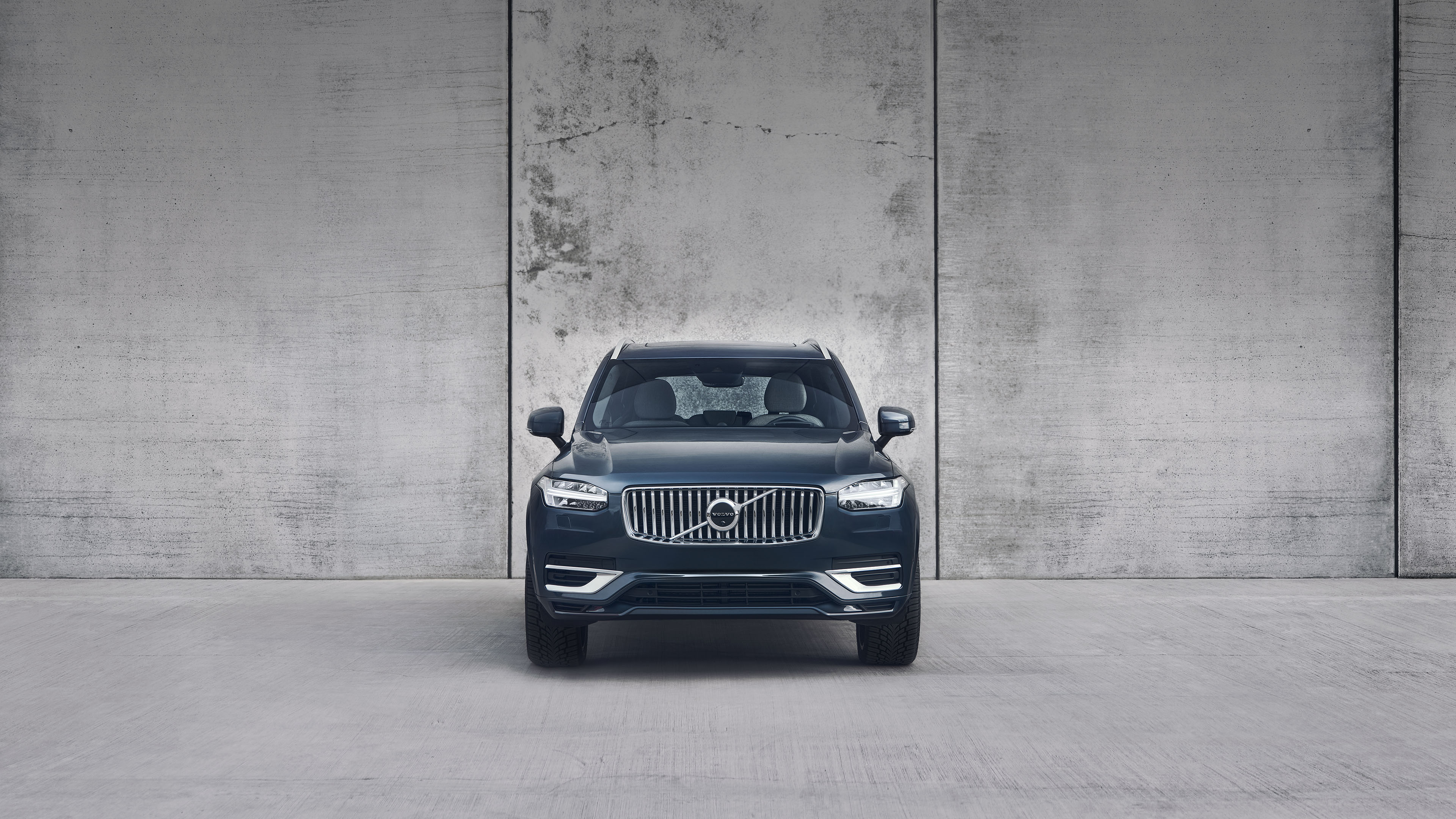 Front facing image of the Volvo XC90 in denim blue with a concrete backdrop.