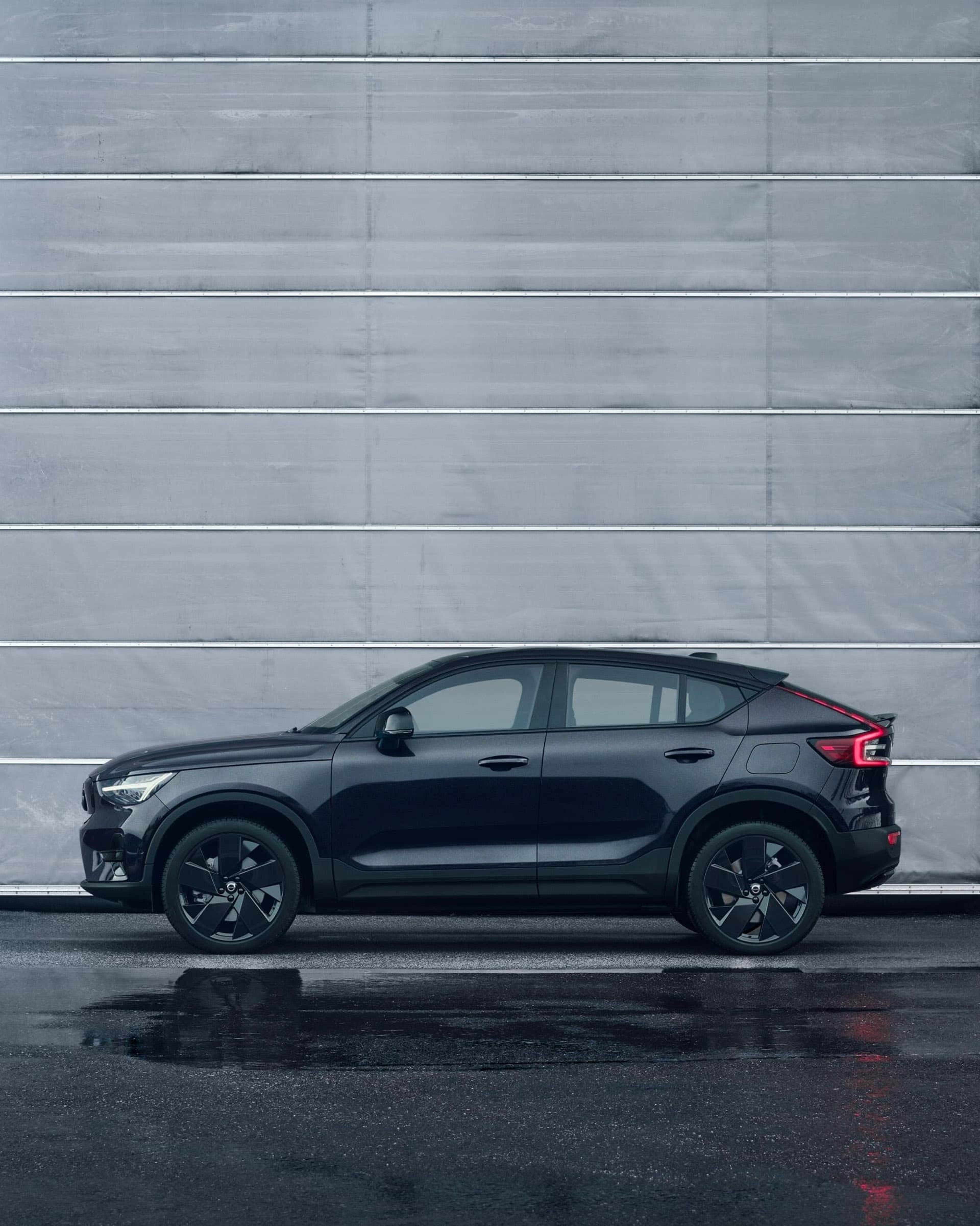 Une Volvo EC40 Black Edition est garée devant une porte de garage grise.