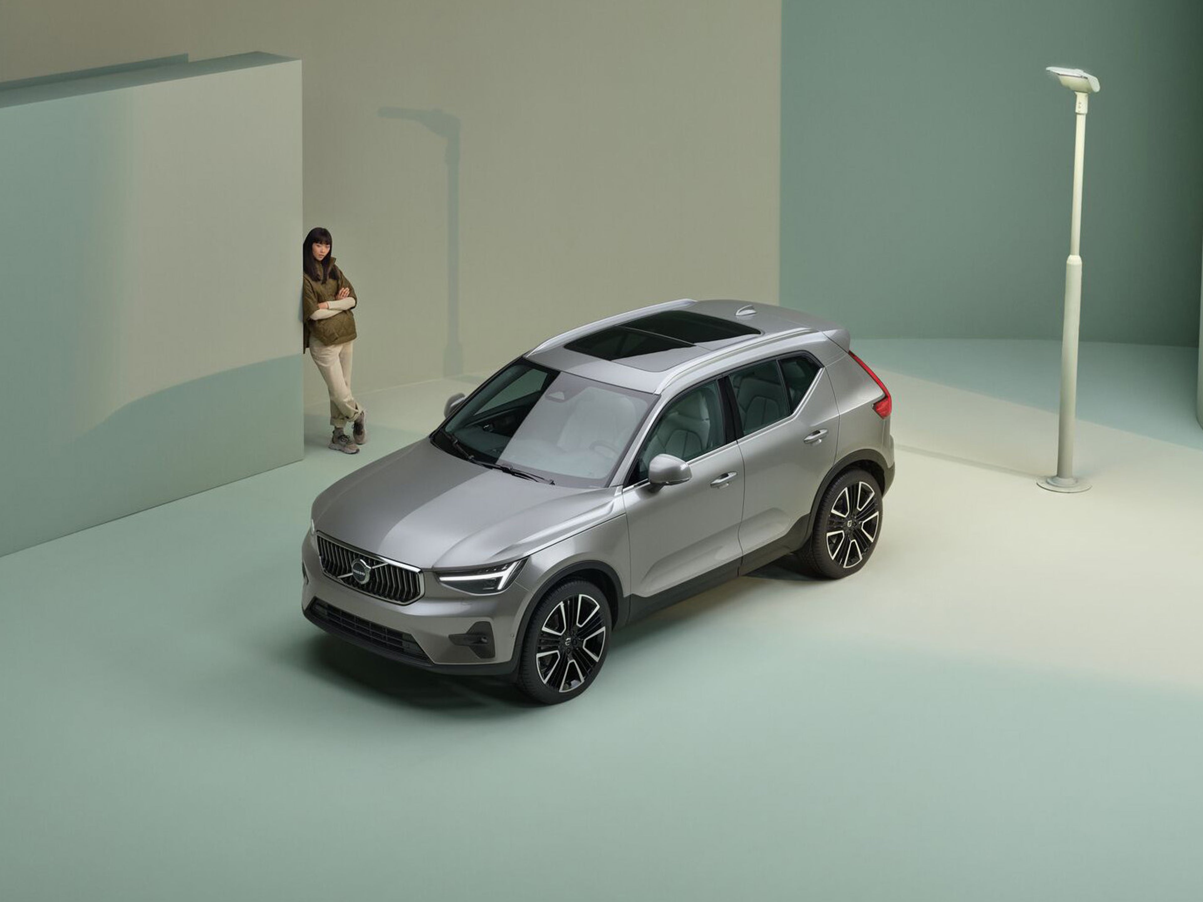 žena stojaca pri zaparkovanom Vovlo xc40 v zelenom prostredí štúdia