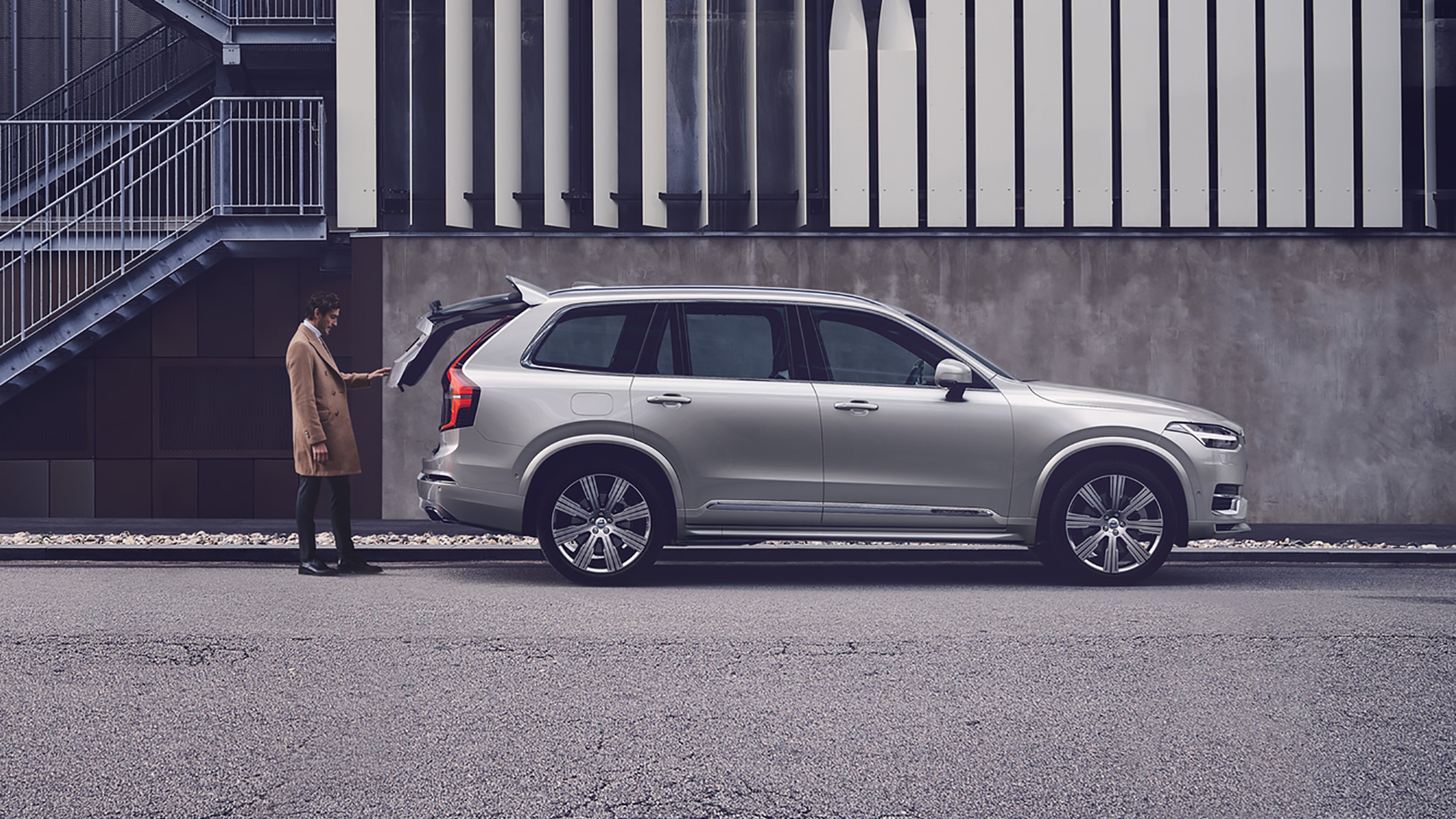 Homme fermant le coffre d'une voiture Volvo de profil