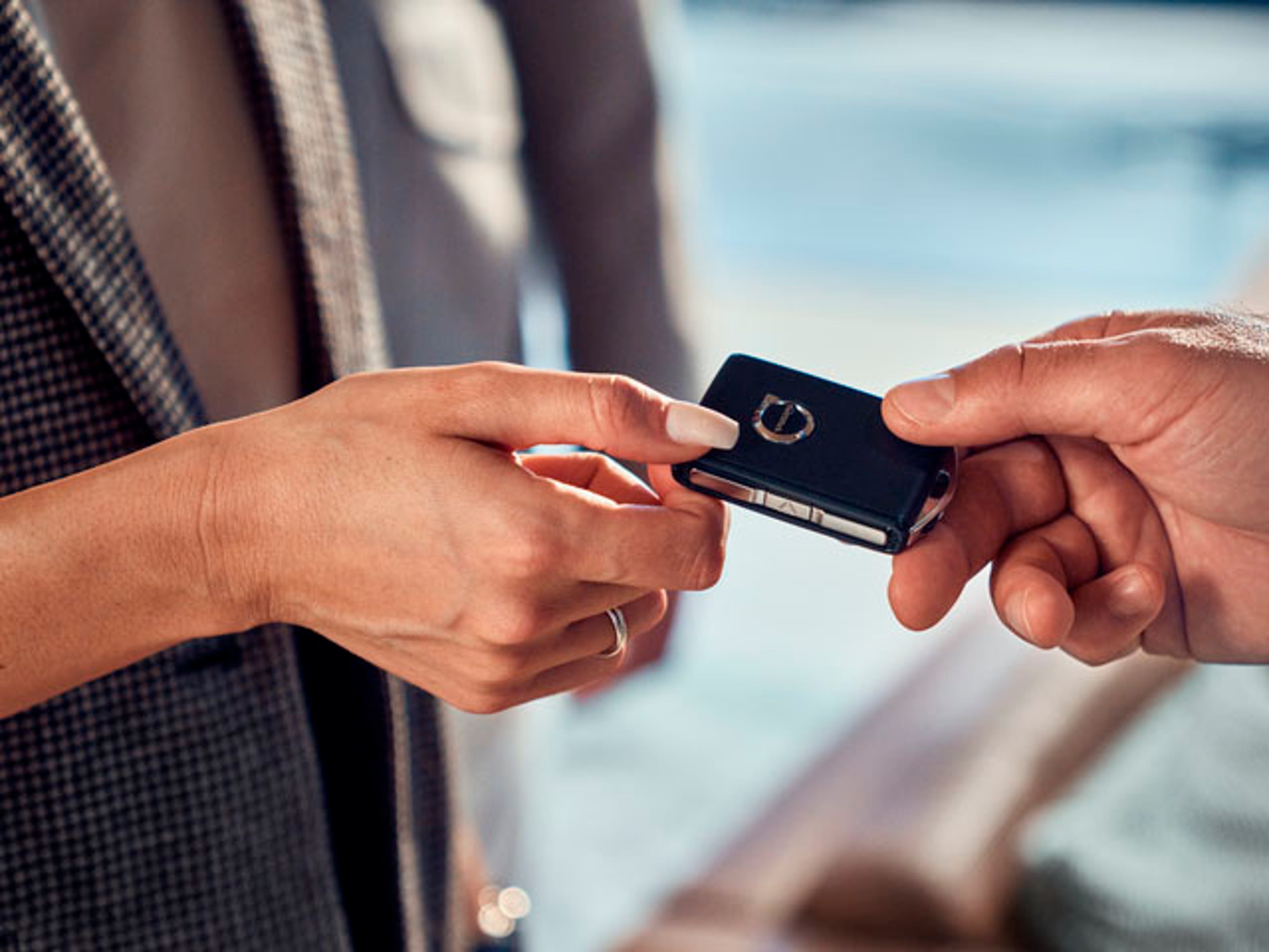 Una mano entregando a otra unas llaves de un vehículo Volvo