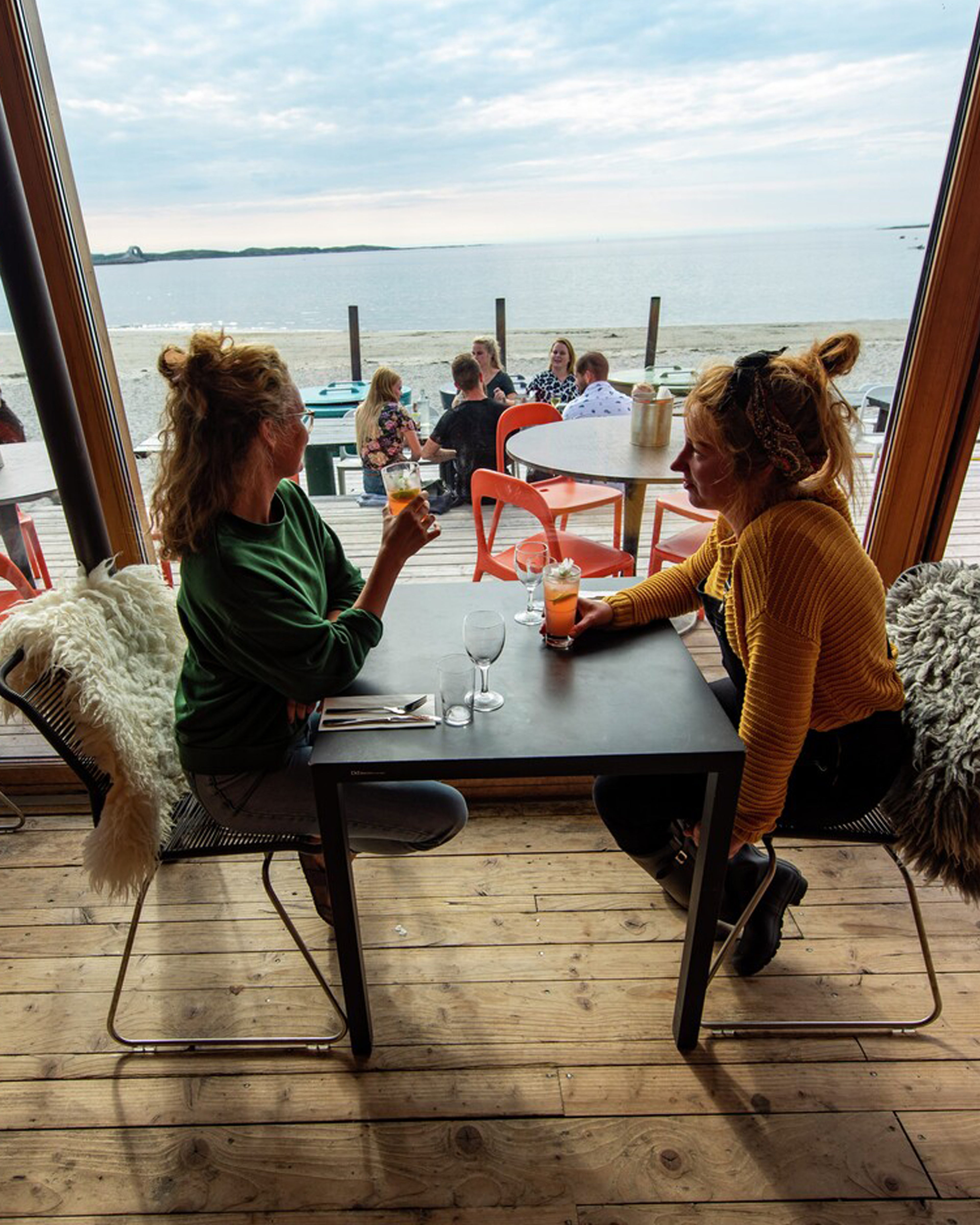 2 damer som sitter på restaurant med havet som utsikt