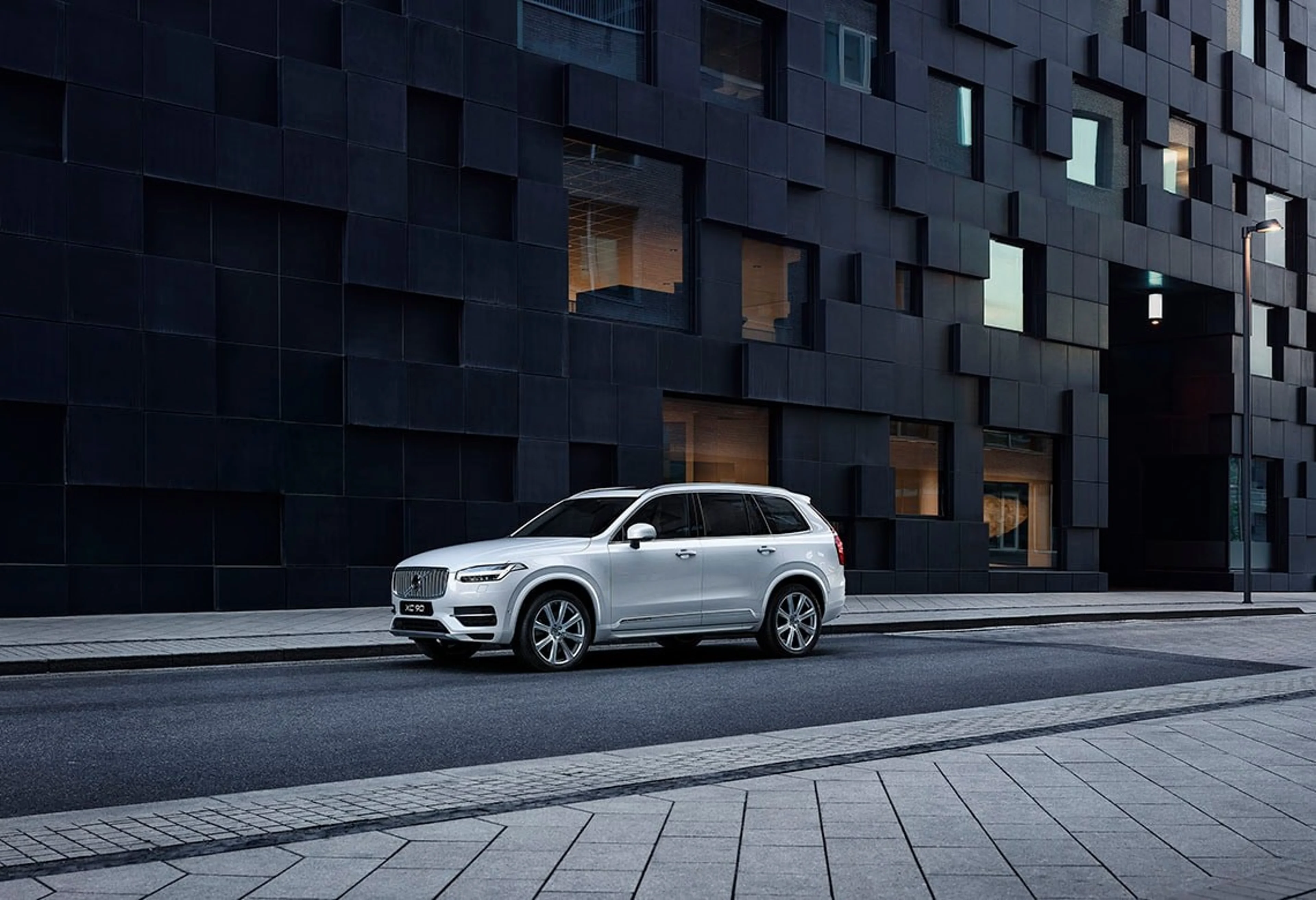 Volvo steht auf einer Straße neben einem schwarzen Gebäude - Frontseitenschuss