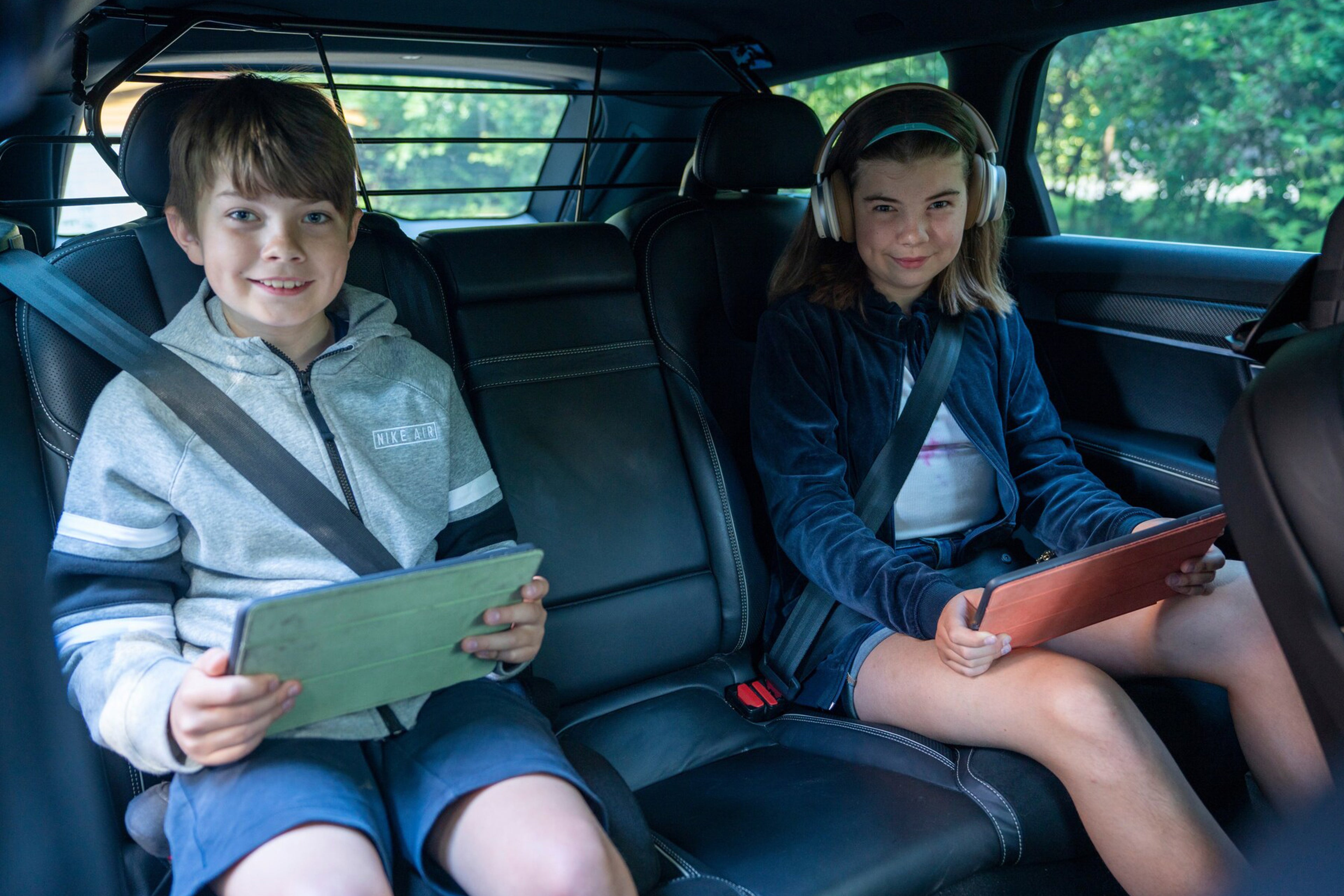 2 fornøyde barn som sitter i baksetet med beltet på