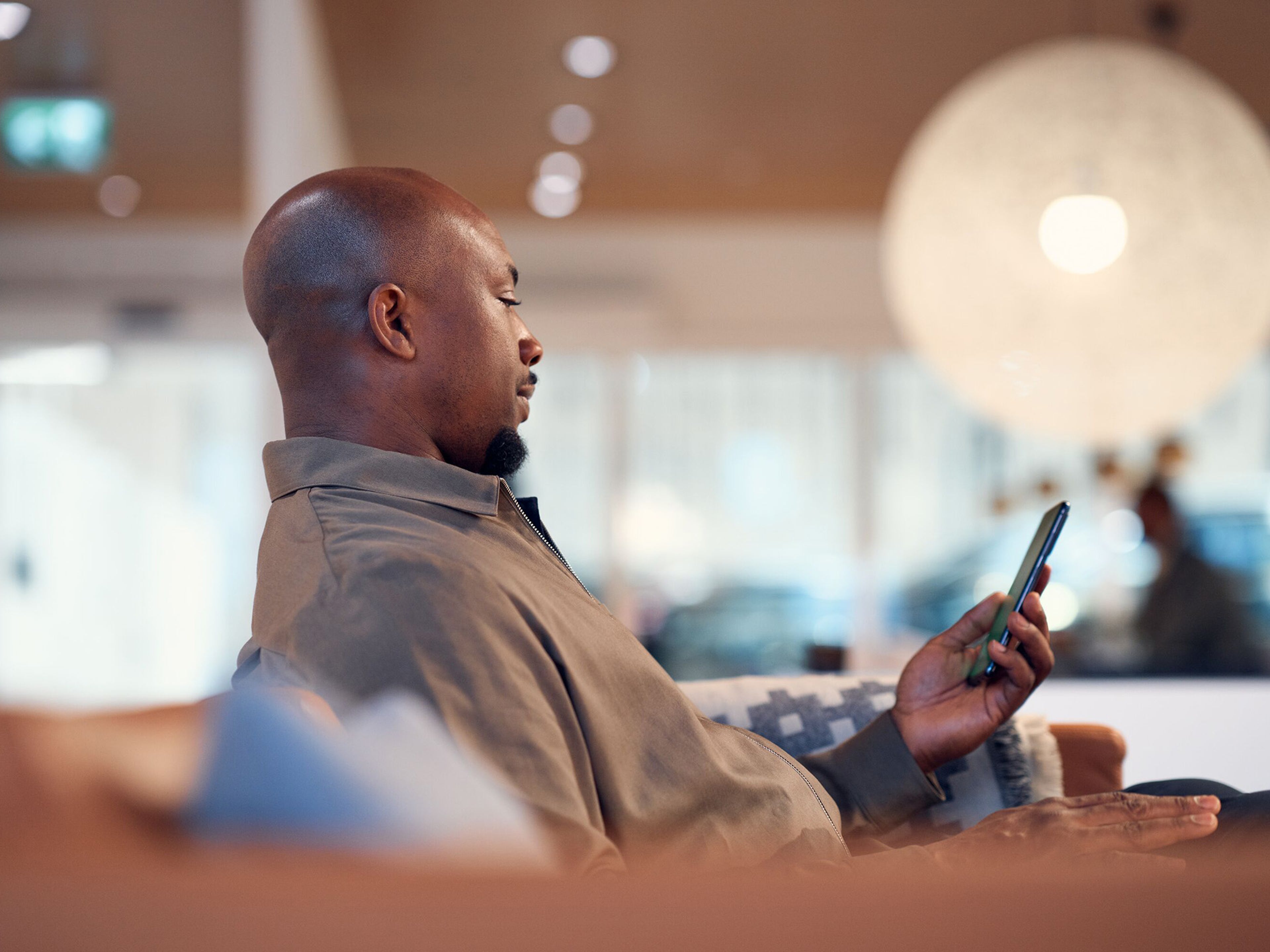 Homem sentado no sofá a fazer marcação de serviço através da app Volvo Cars