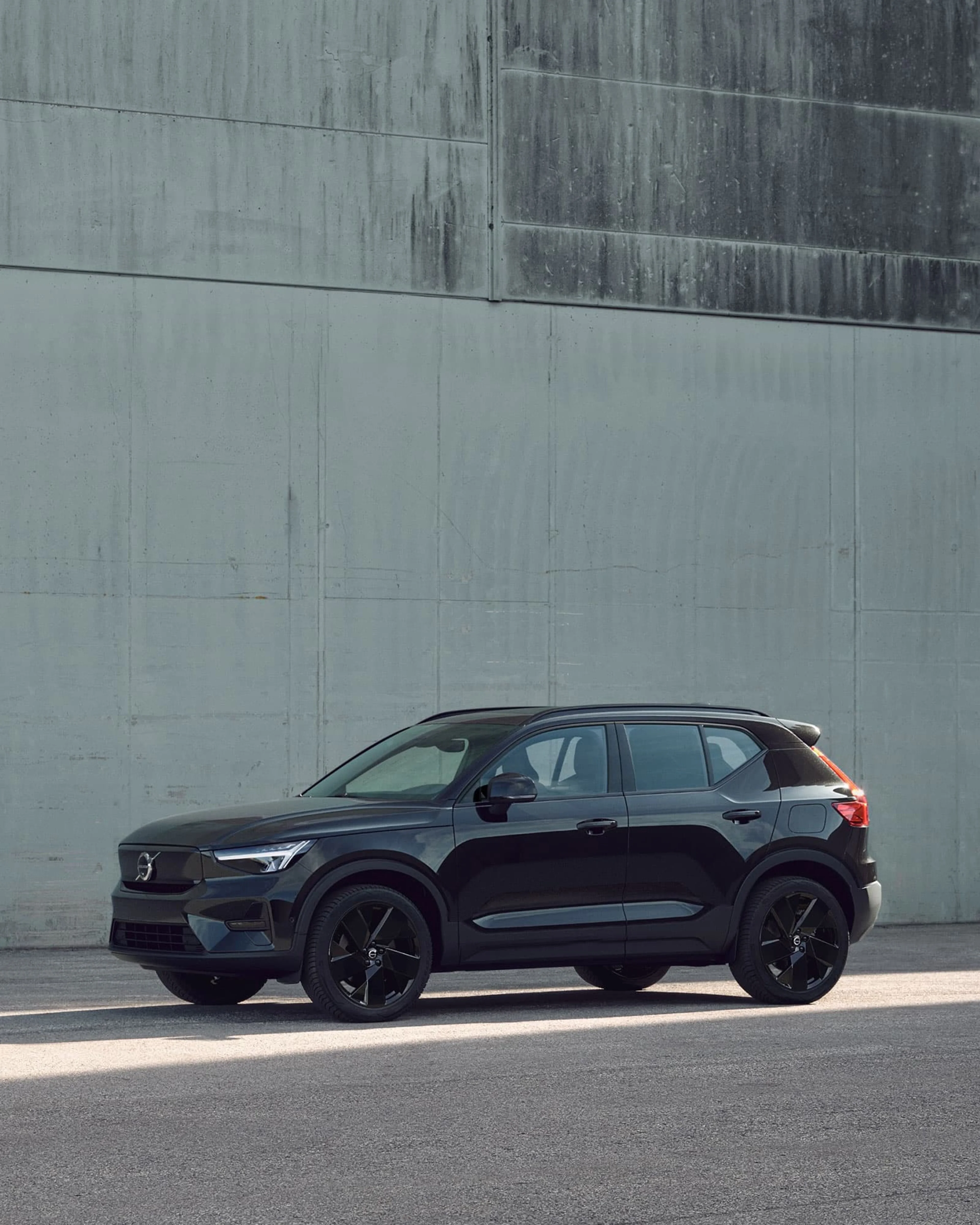 Een Volvo EX40 Black Edition is geparkeerd voor een betonnen muur.