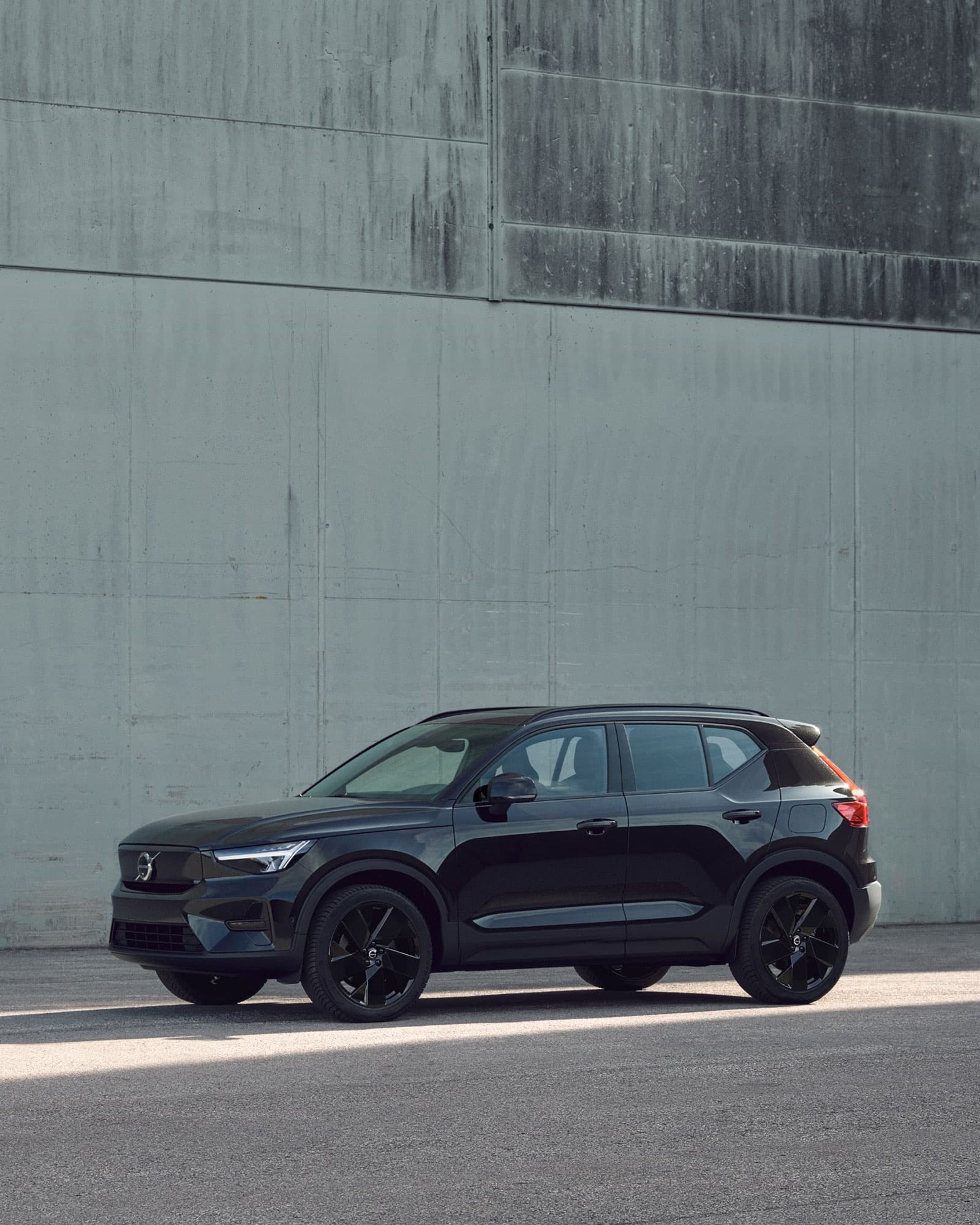Une Volvo EX40 Black Edition est garée devant un mur en béton.