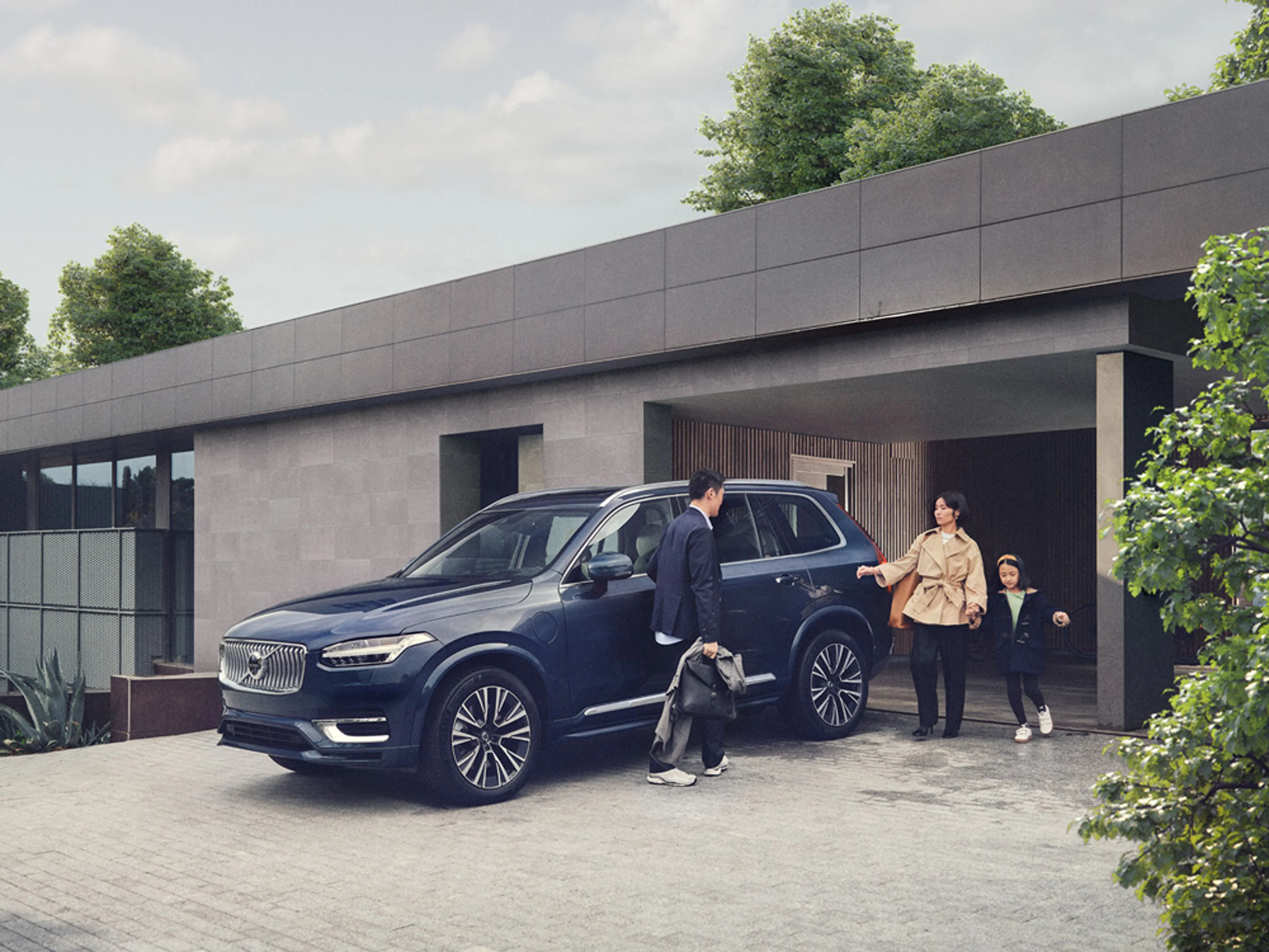 Une famille recharge sa Volvo électrique avant son garage.