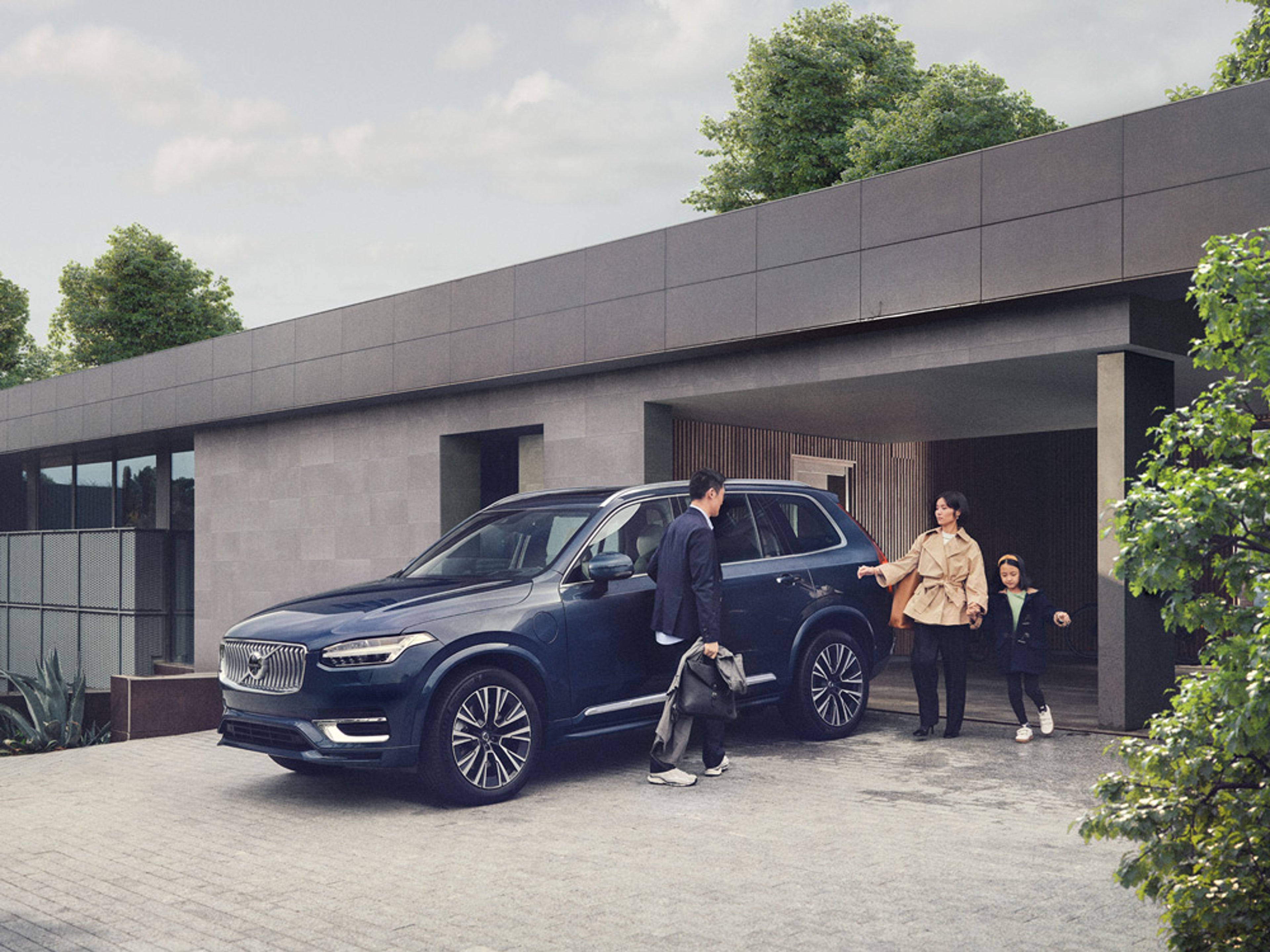 Une famille recharge sa Volvo électrique avant son garage.