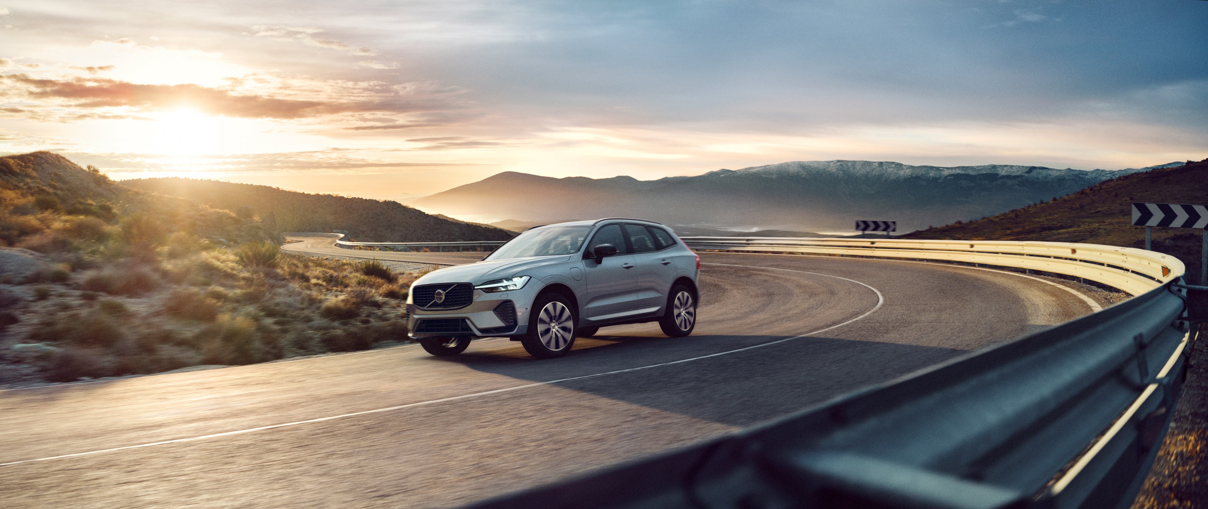 Volvo XC60 jazdiace v zákrute pri západe slnka