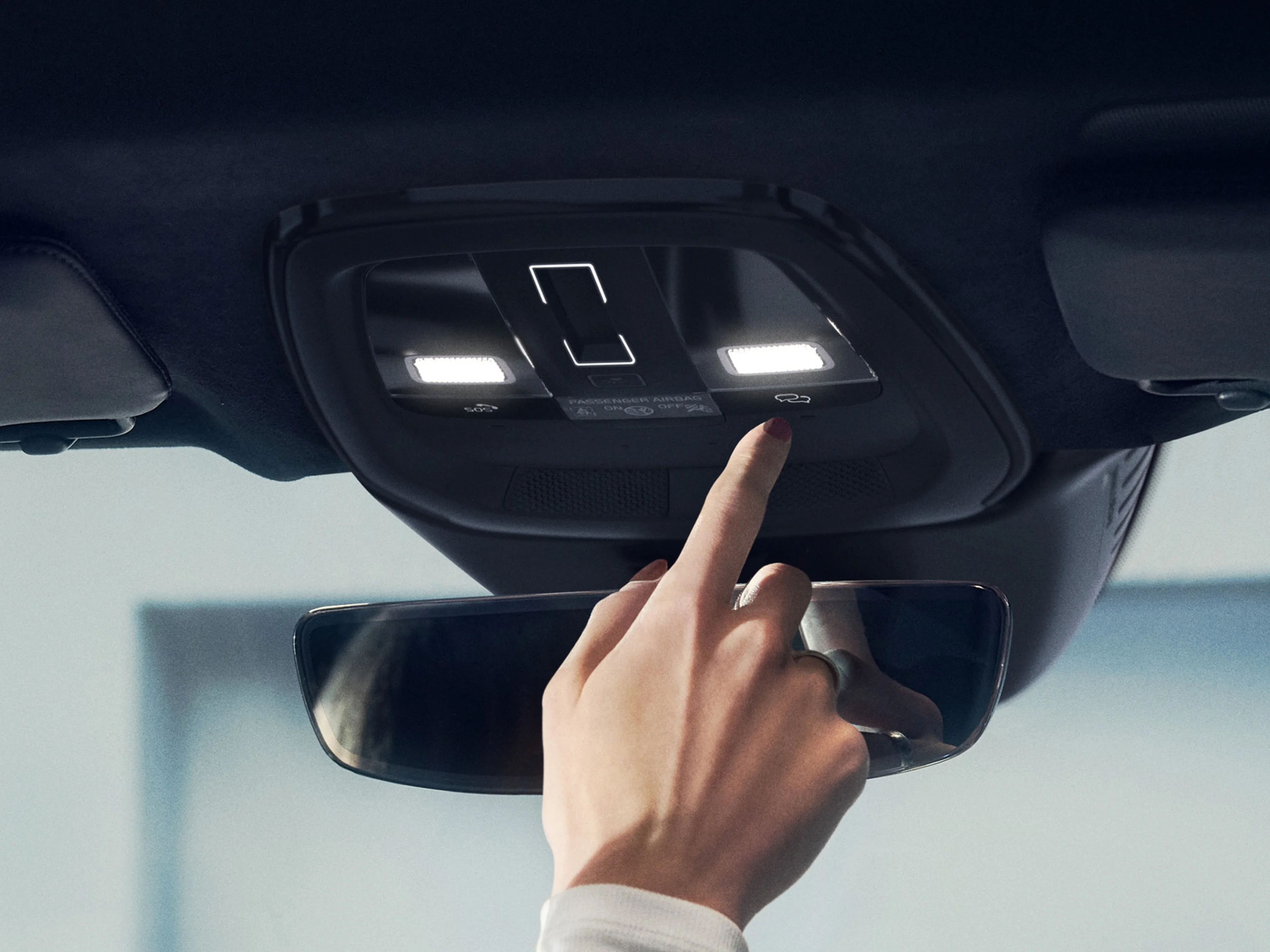 Volvo driver pressing Volvo Assistance button in overhead console