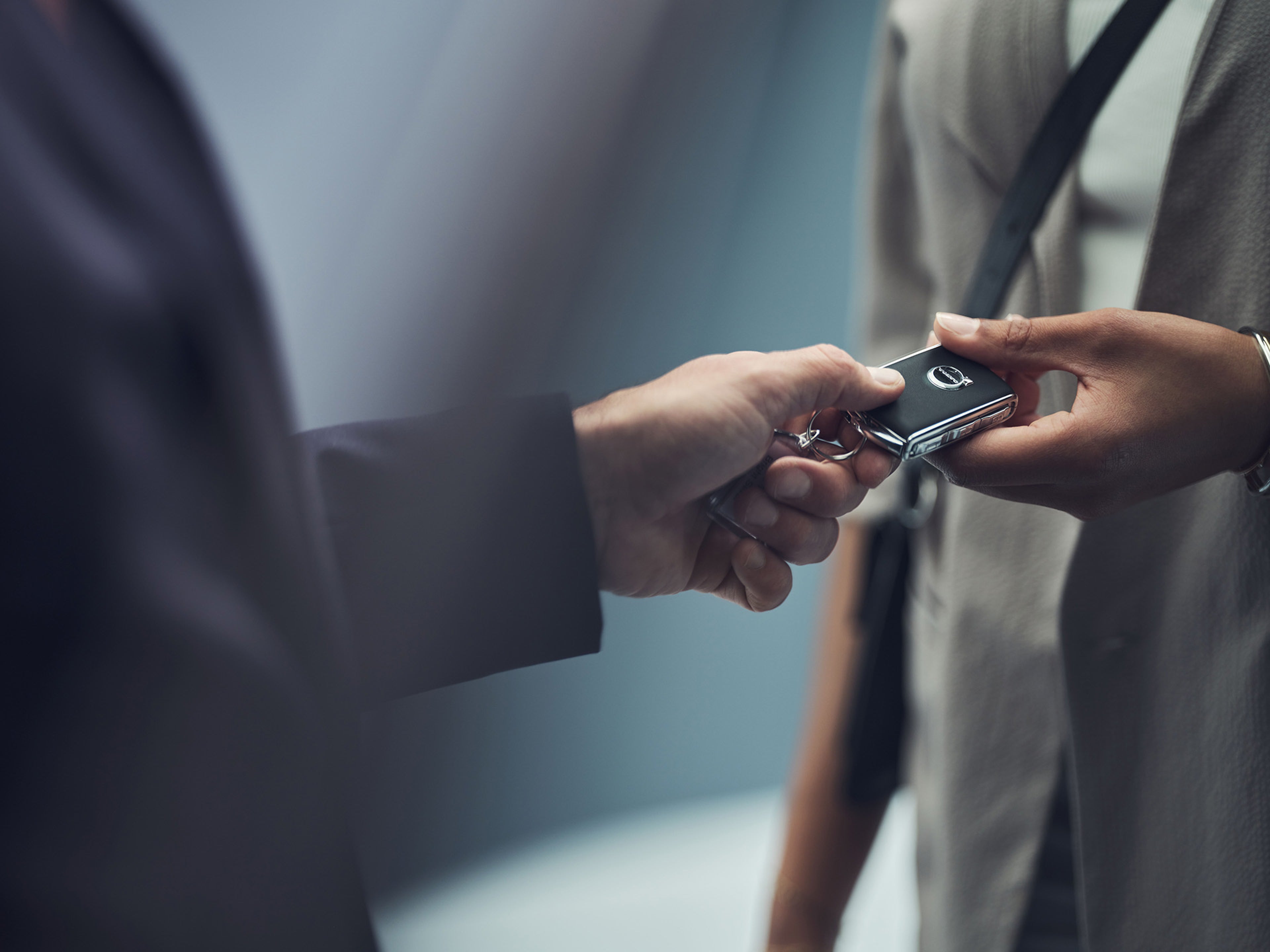Duas pessoas a trocar a chave de um Volvo, com foco nas mãos.