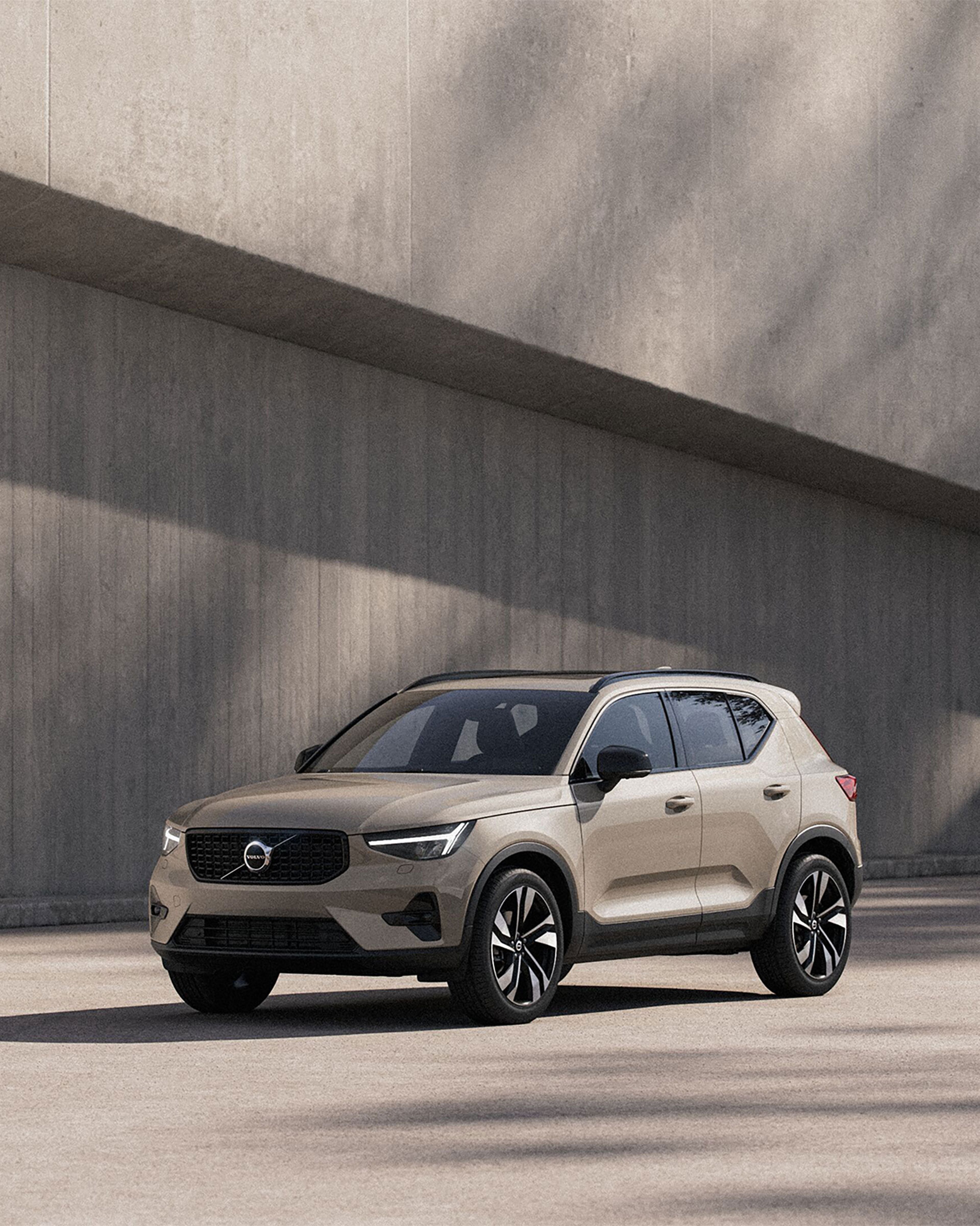 Volvo XC40 beige garé devant un mur en béton, SUV compact au design scandinave avec jantes bicolores et toit noir
