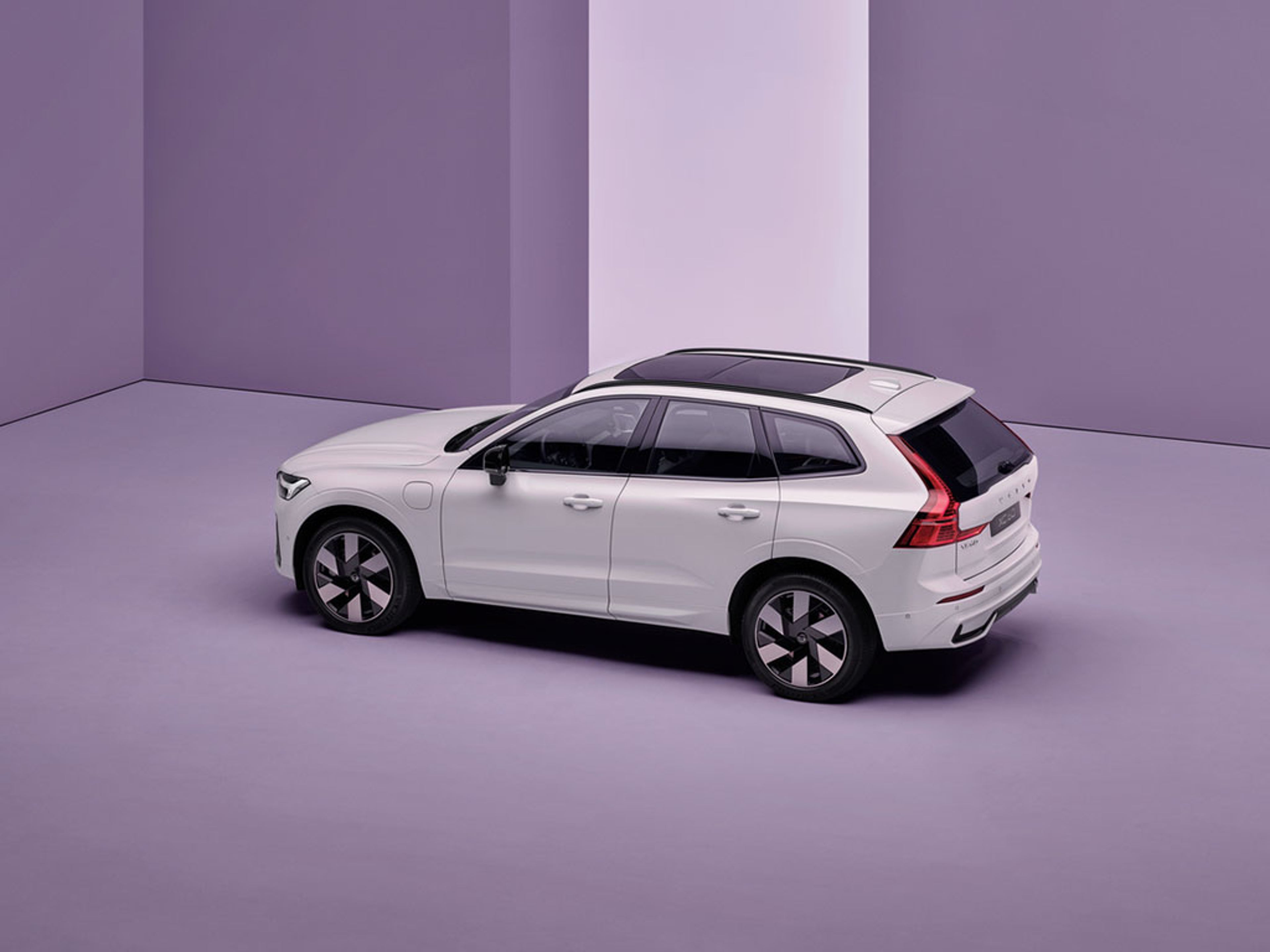 SUV blanc garé dans une pièce violette minimaliste avec une bande verticale blanche sur le mur.